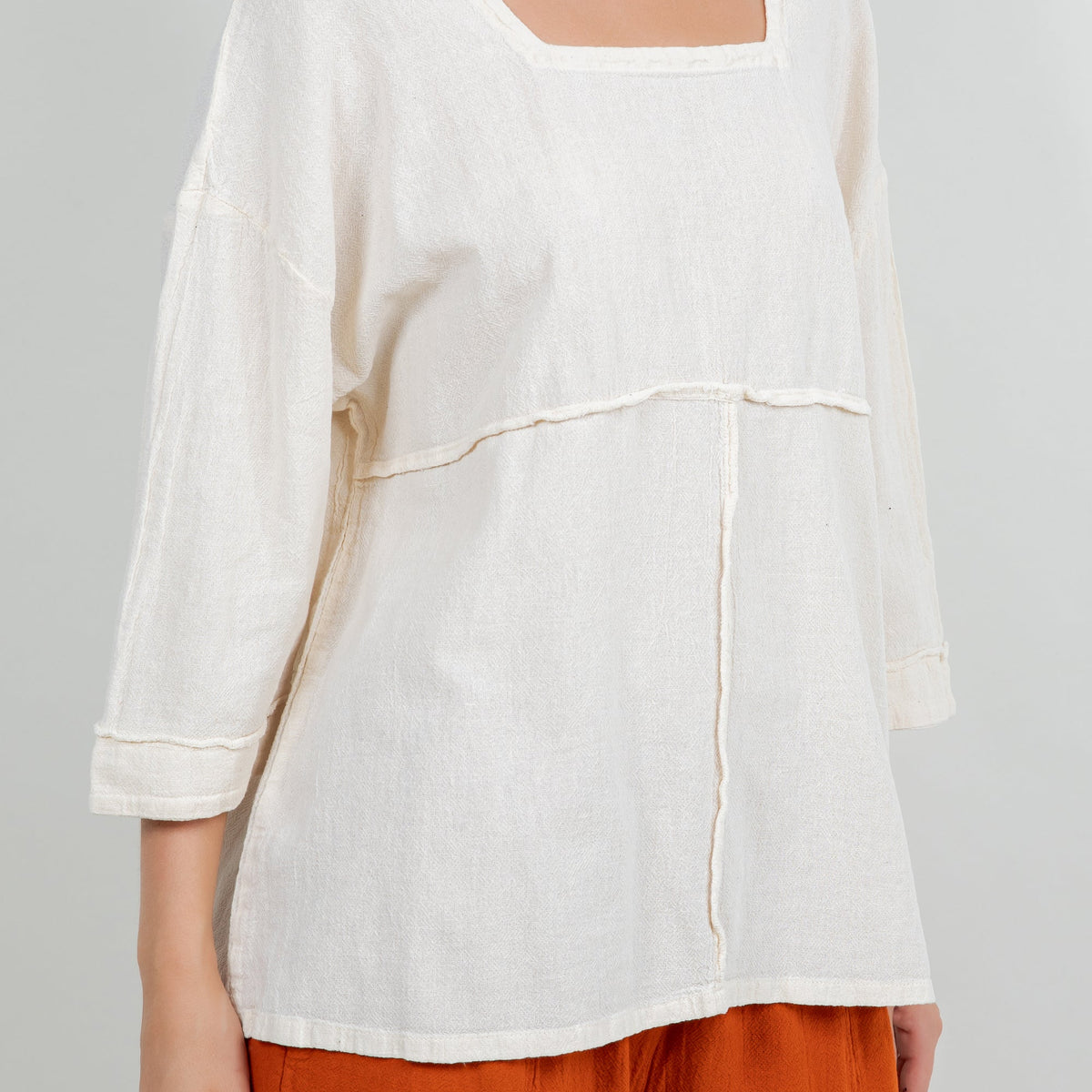 White cotton gauze top close view with square neck and curved seam across chest