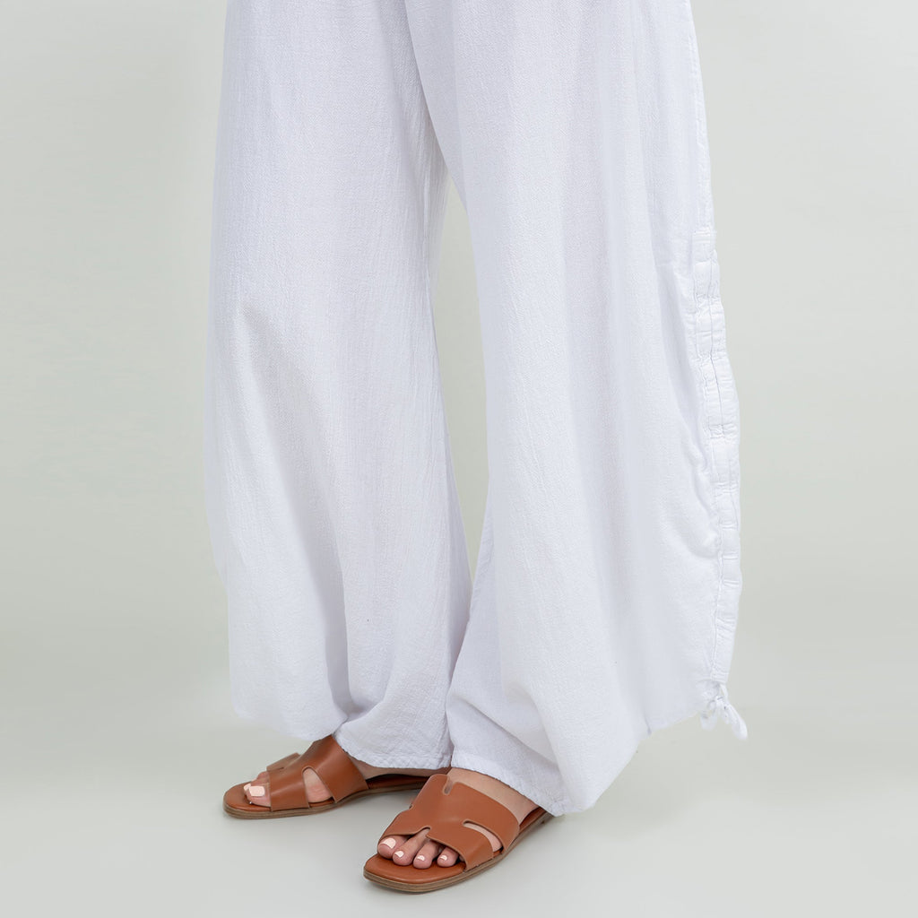 White cotton gauze pants close-up: elastic waist and side-tied tassel hem
