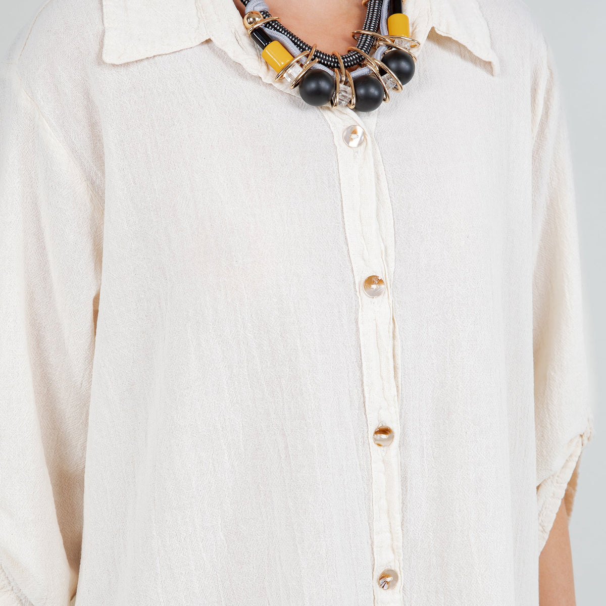 White cotton gauze tunic detail, button-front placket and collar, three-quarter sleeves.