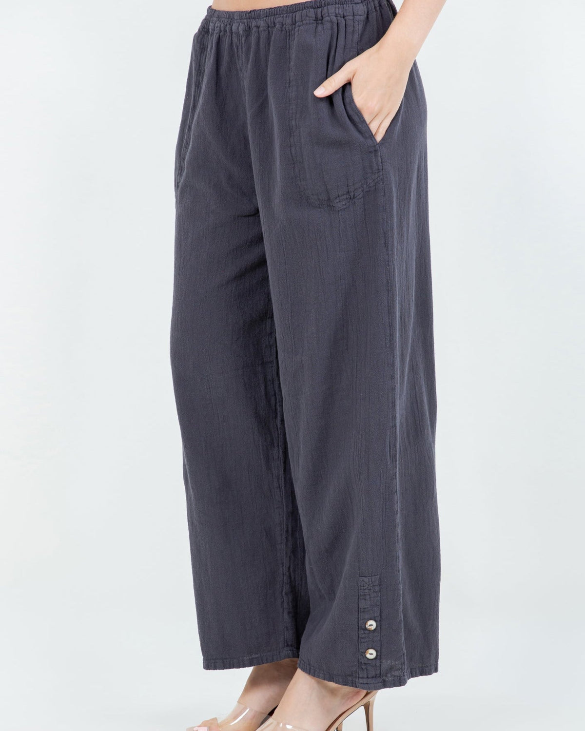 Dark charcoal cotton gauze pants with elastic waist, relaxed wide legs, and button hem