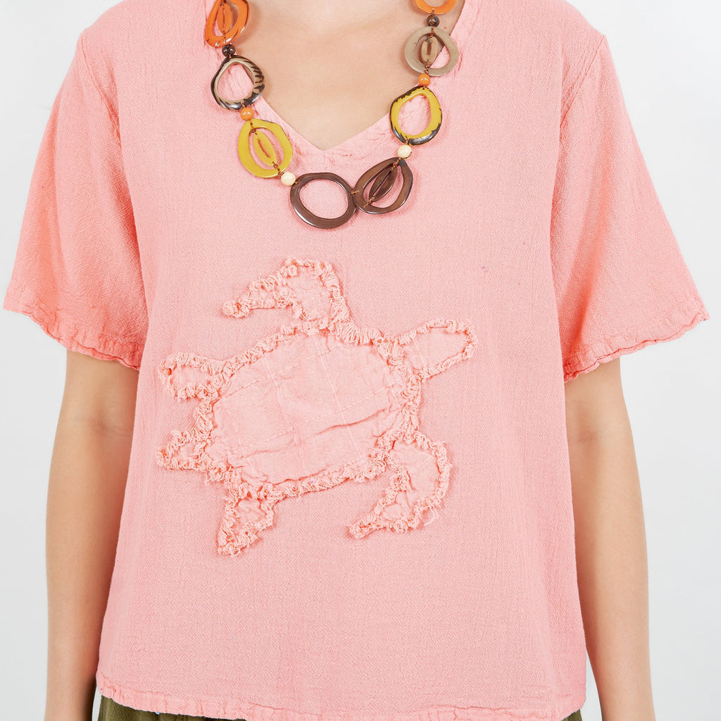 Close-up of women’s pink cotton gauze top with embroidered applique and V-neck