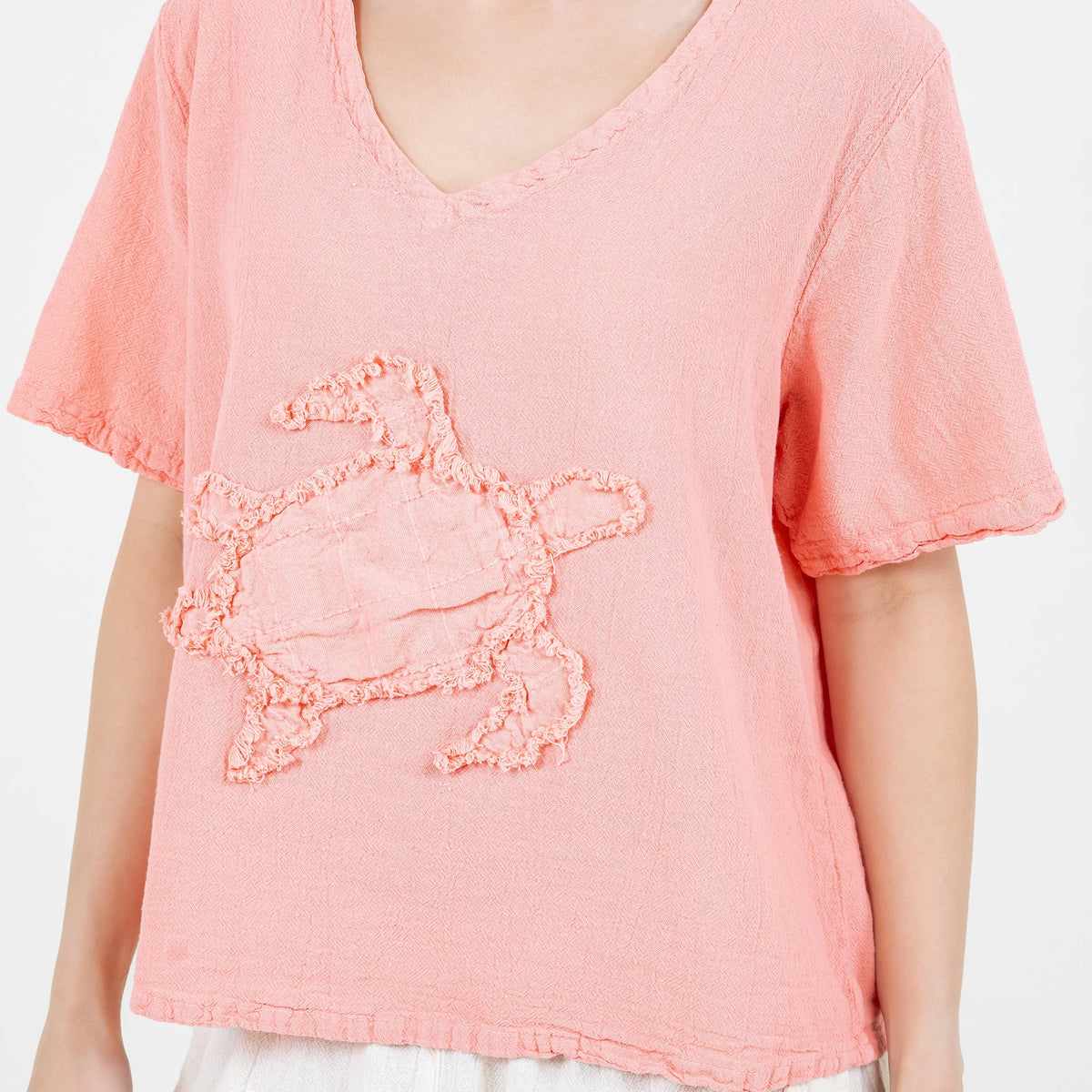 Peach cotton gauze turtle top close-up: V-neck with embroidered turtle design