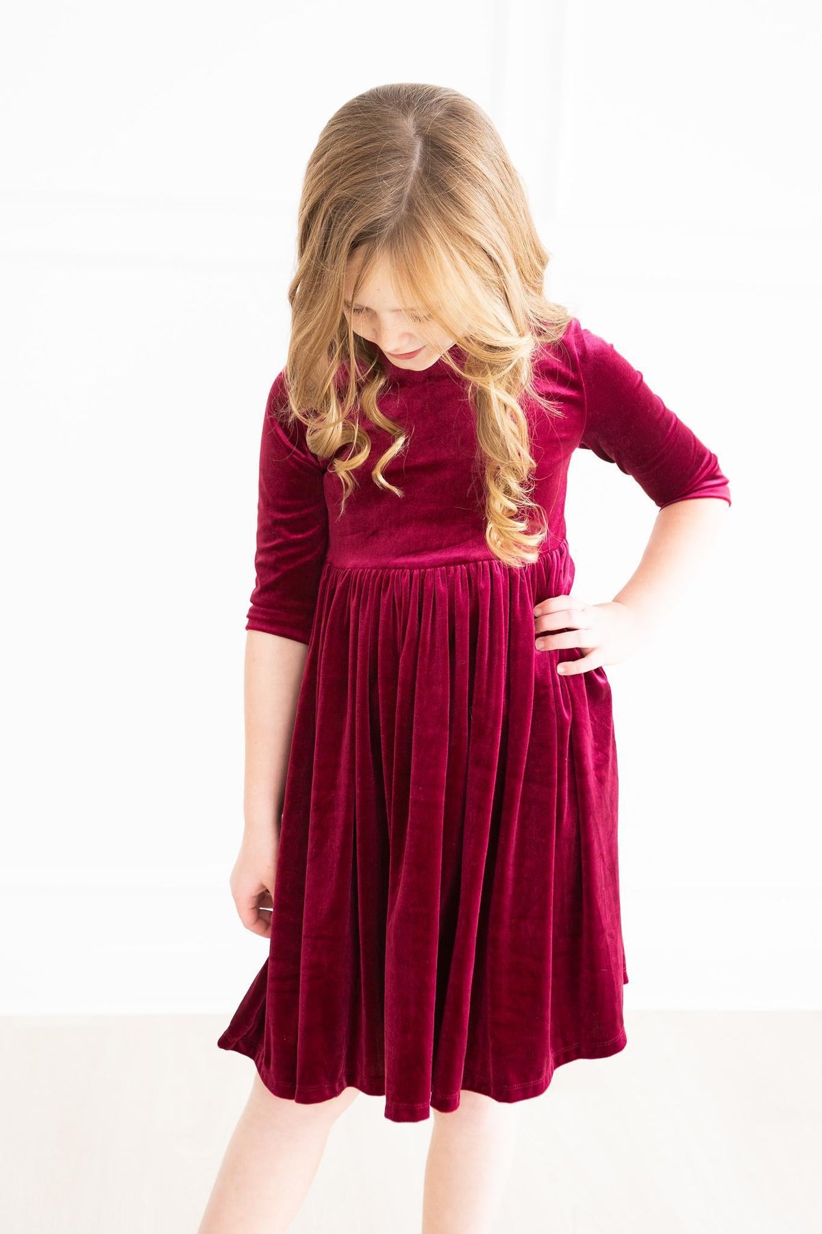 Cranberry velvet twirl dress with 3/4 sleeves, empire seam, and pleated skirt