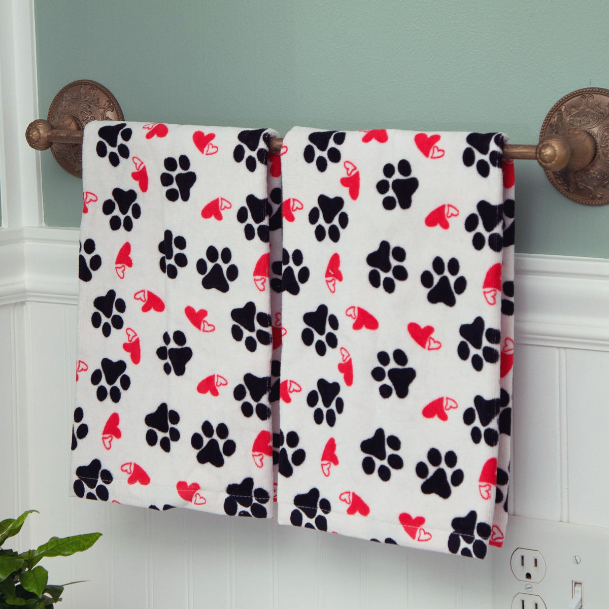 Two bath hand towels hanging side by side: white with black paw prints and red hearts