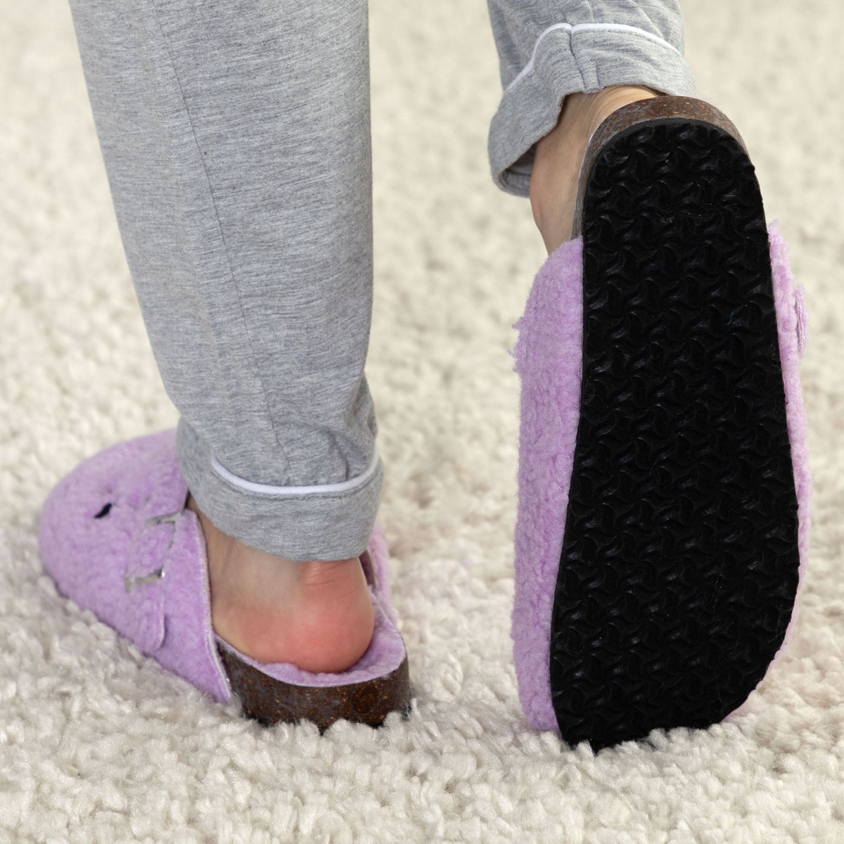 Purple plush sherpa clog slippers with brown sole trim and black tread bottom