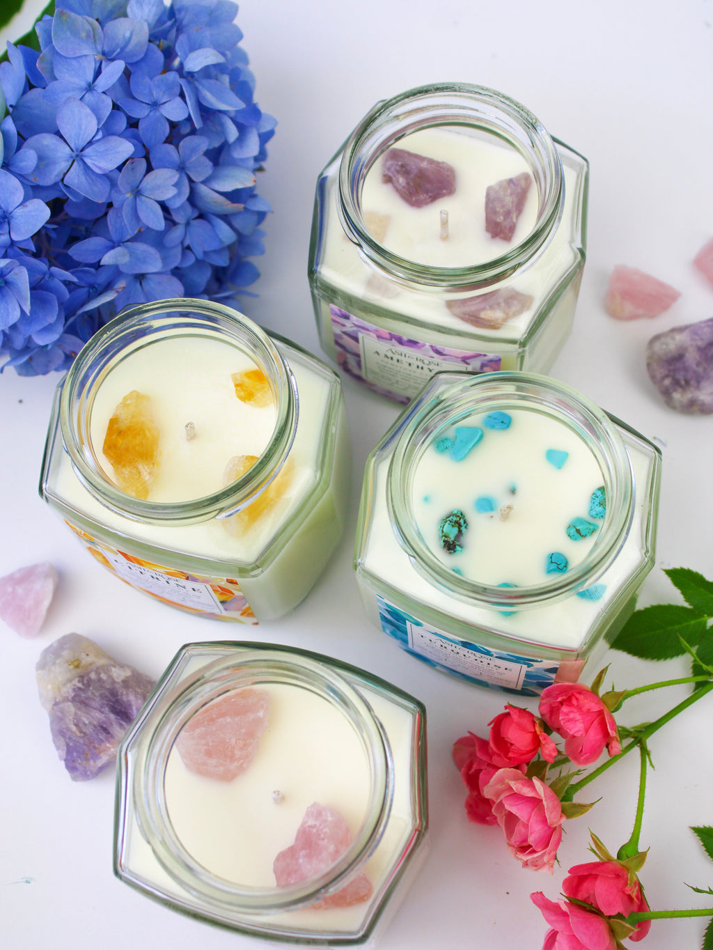 Assorted gemstone candles in clear glass square jars with embedded crystal pieces