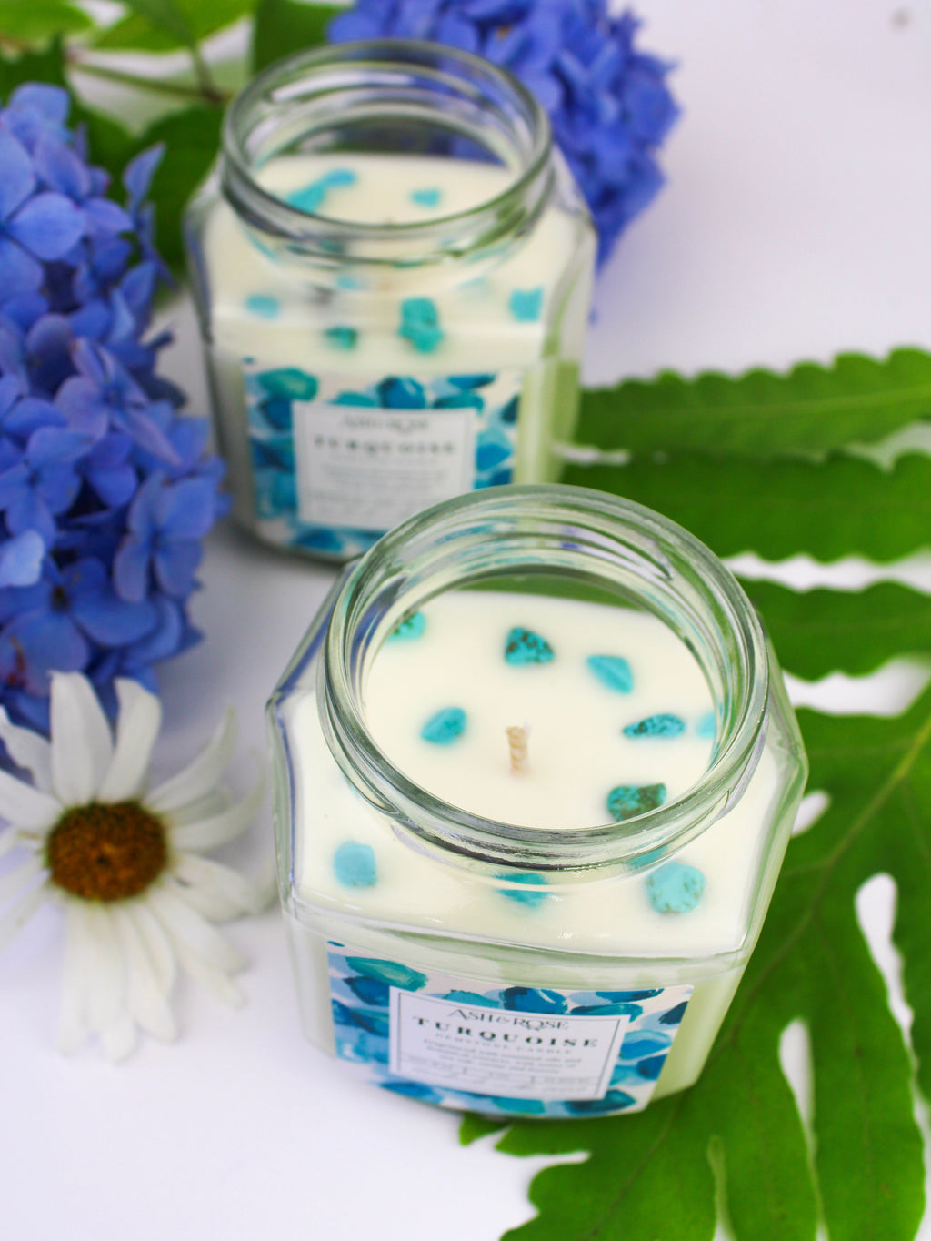 Turquoise gemstone candle in clear glass jar with scattered blue crystal fragments