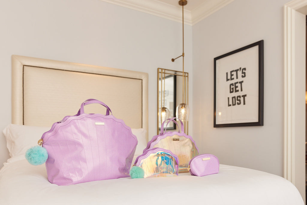 Mermaid travel luggage set on bed: lavender tote, iridescent bag, and zip pouch