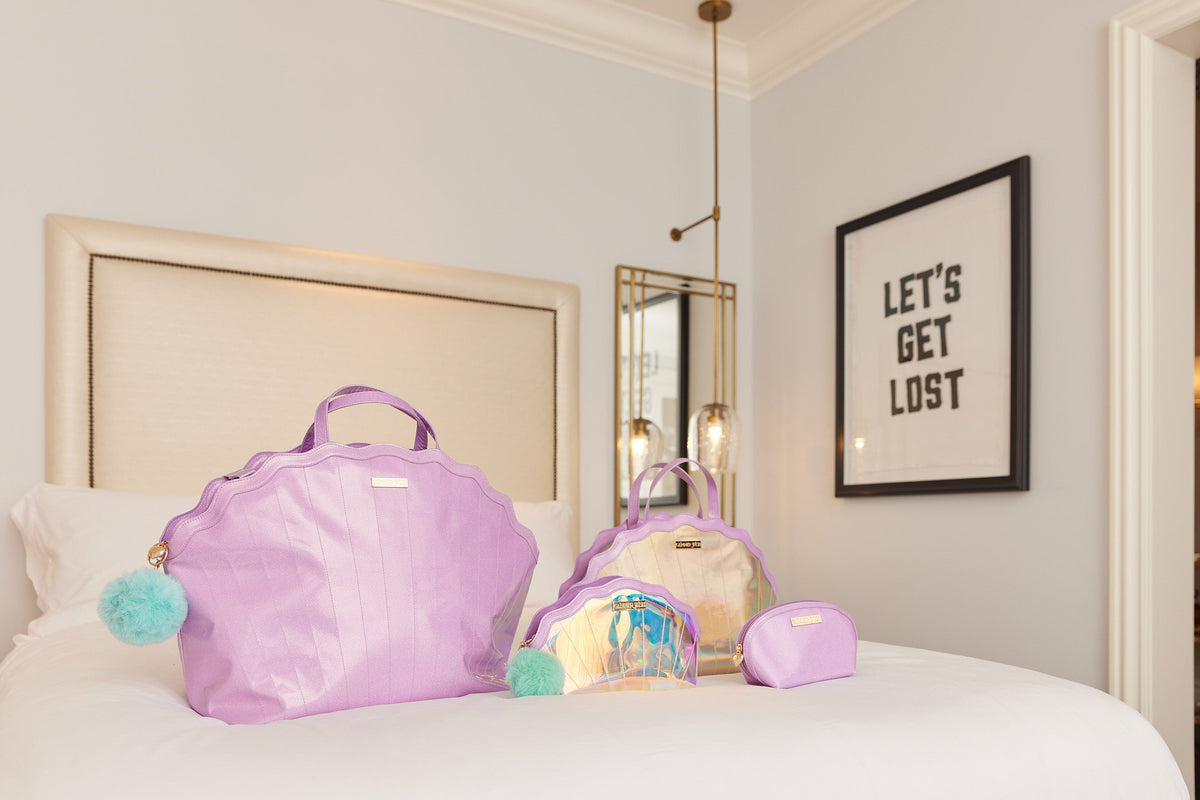 Mermaid travel luggage set on bed: lavender tote, iridescent bag, and zip pouch