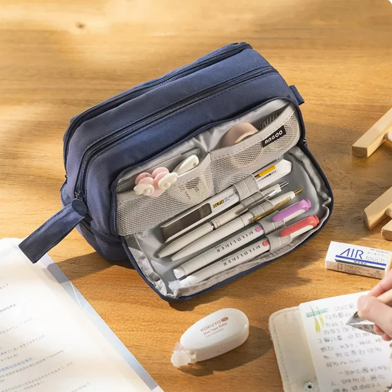 Dark blue zippered pencil bag open on desk, showing pencils in front compartments.