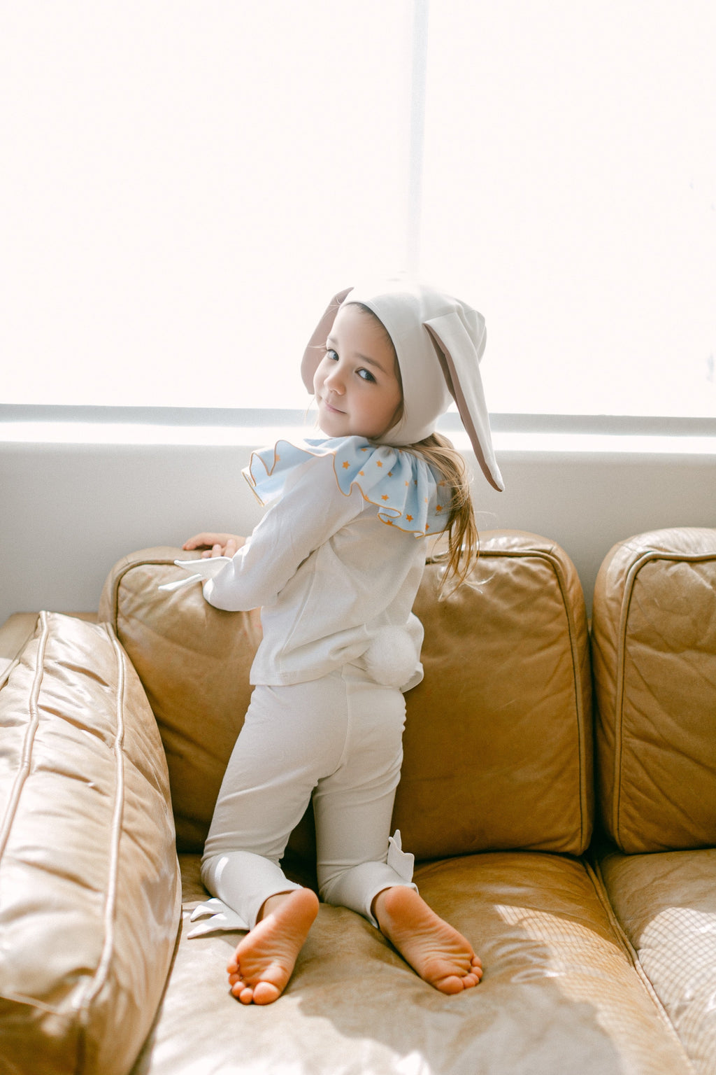 Baby bunny costume with blue star bib, white hood, and flared sleeves