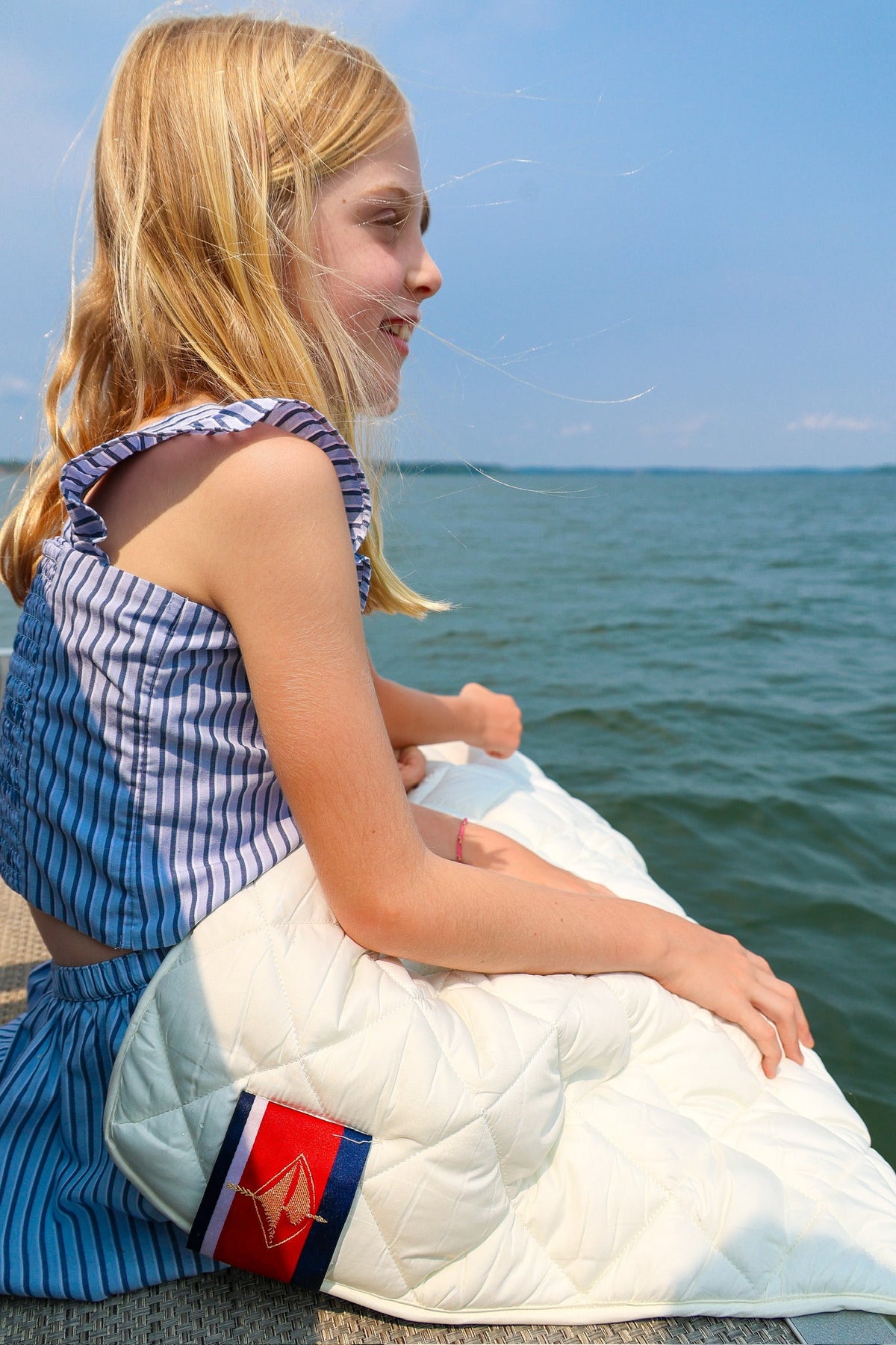 Waterproof puffer blanket with pockets, white quilted blanket on a seat by the water