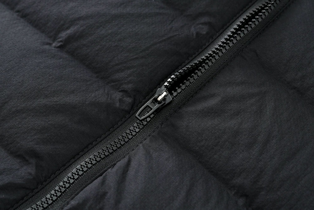 Black down jacket zipper with metal pull, front seam detail