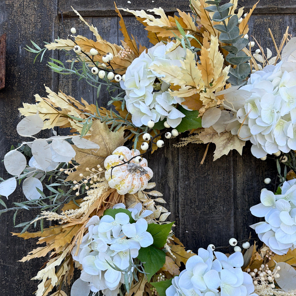 Truffle wreath featuring large white hydrangea clusters, tan foliage, eucalyptus, and round beads.