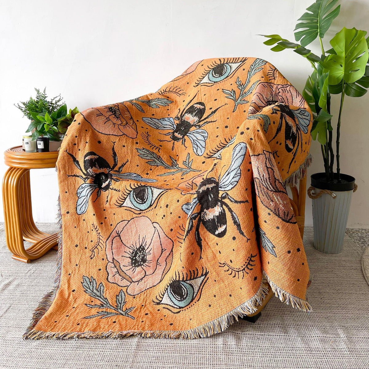 Floral and eye patterned throw blanket in rust orange with fringed edges