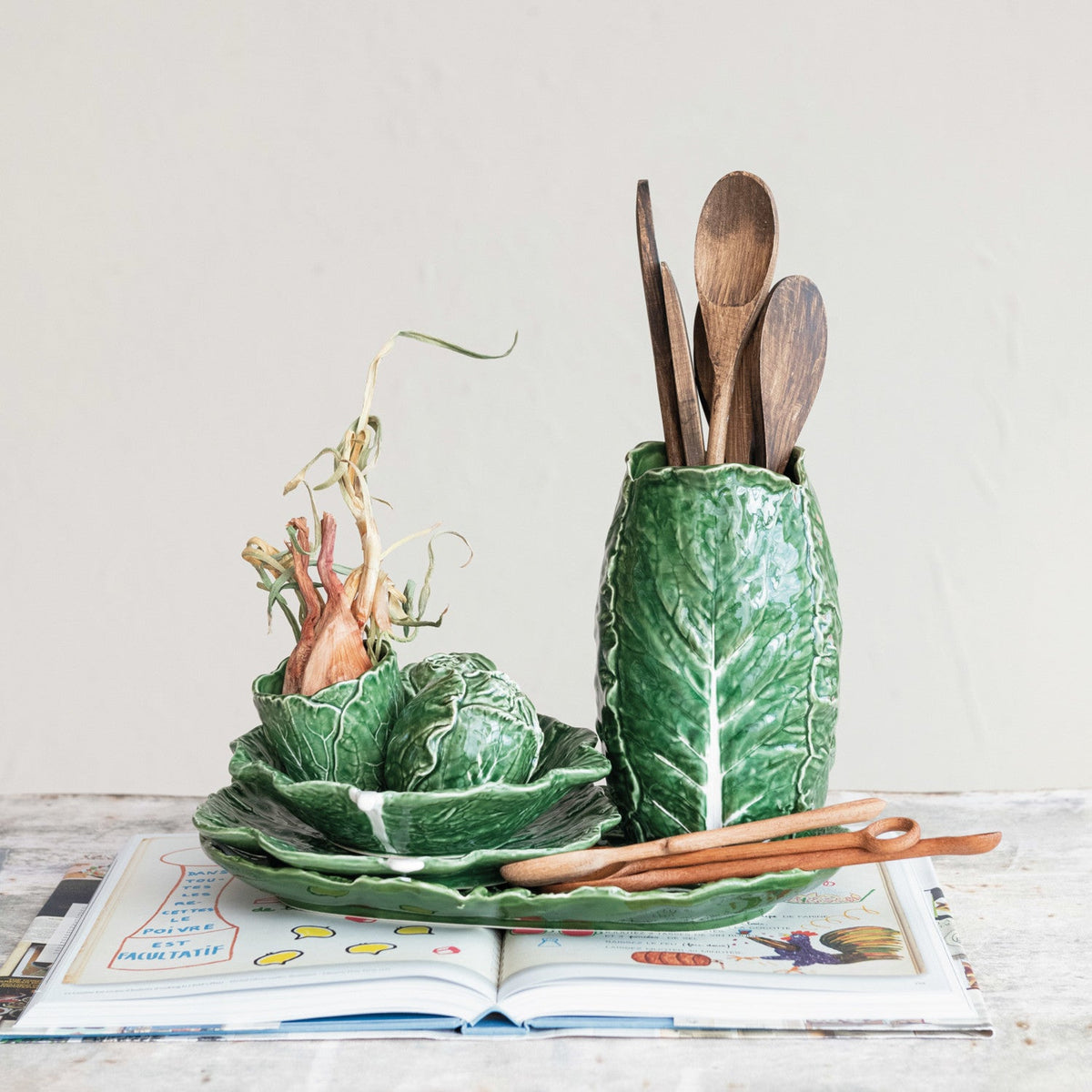 Green leaf-shaped ceramic plate on table, hand-painted with veining