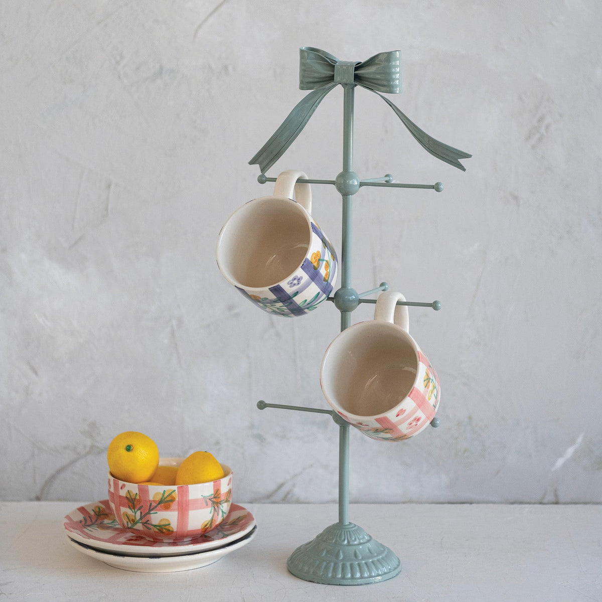 Ceramic mug pair hanging on a teal stand, with mixed botanical and grid patterns