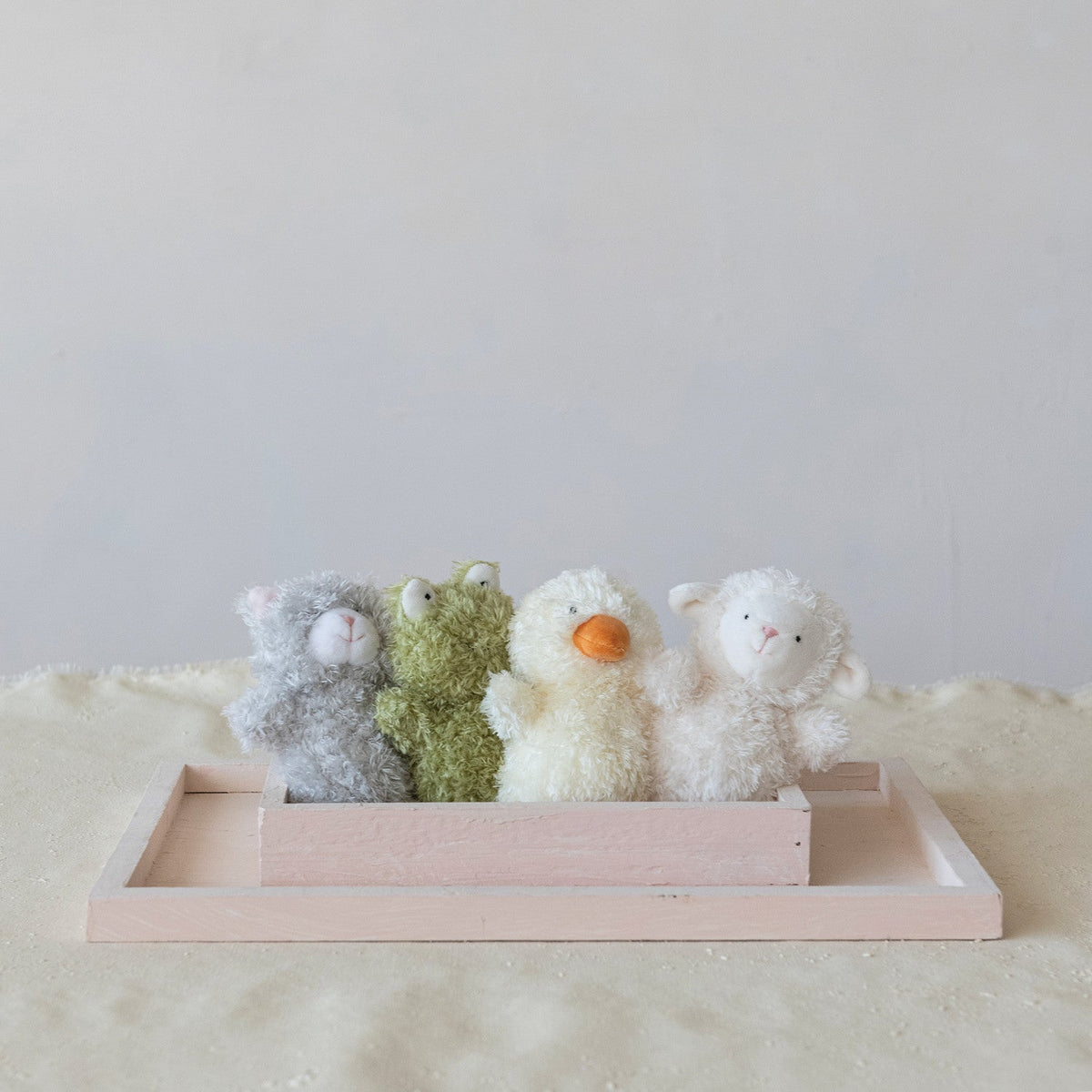 Plush bean bag stuffed animals in a wooden tray: gray, cream, green, and white styles