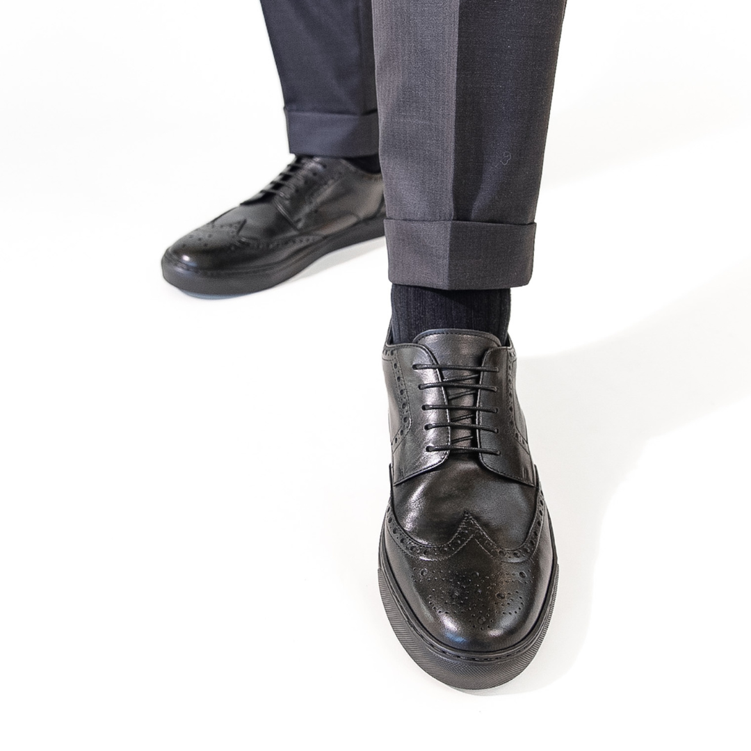 Black lace-up dress shoes with wingtip design and textured toe perforations