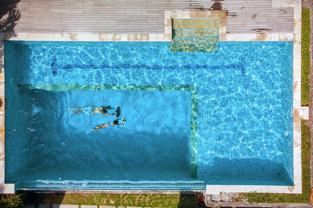 Underwater drone in a pool with visible smartphone controller on the deck