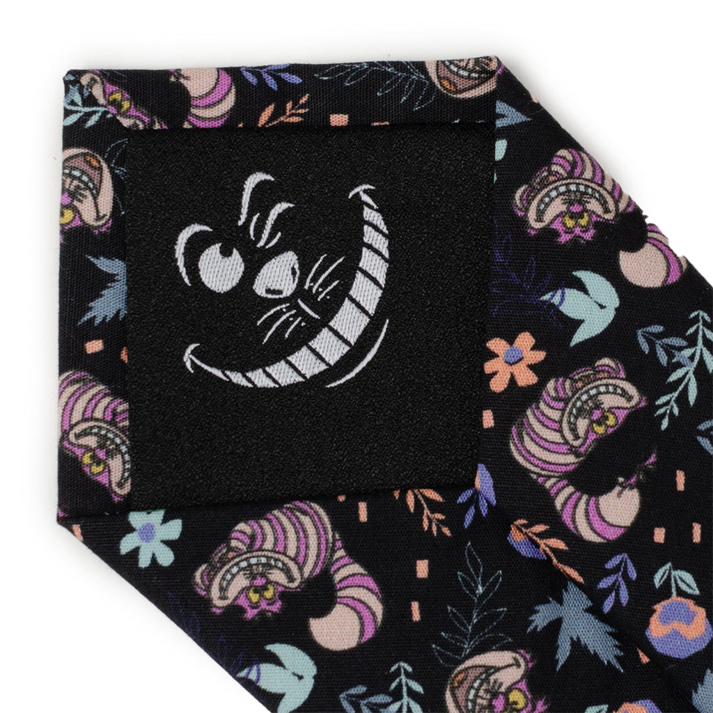 Black tie fabric close-up with Cheshire Cat face print and floral accents
