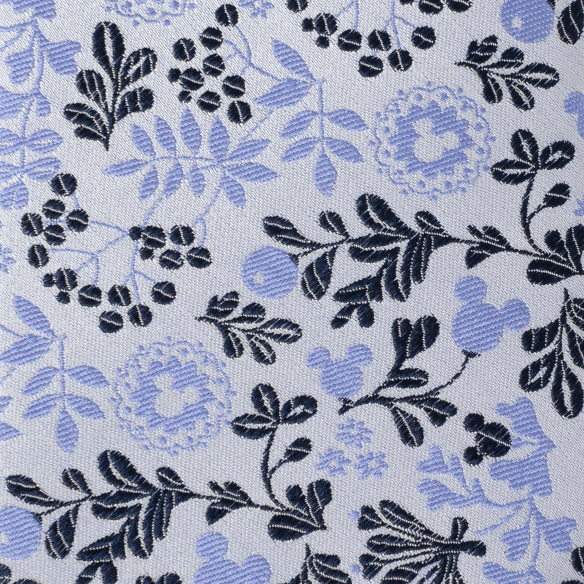 Blue and white floral necktie close-up with dark leaves and light blue blossoms