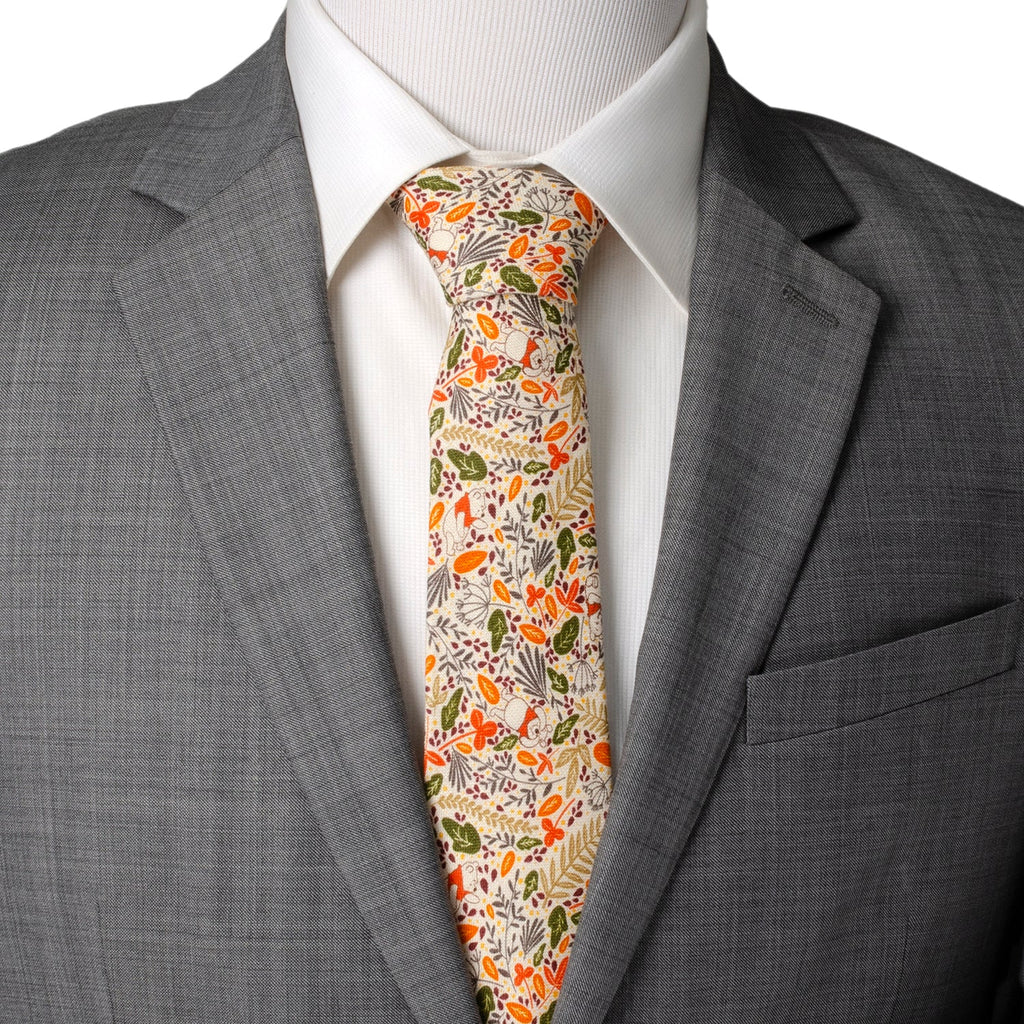 Men's tie worn with gray blazer; cream background with orange, green, and red pattern