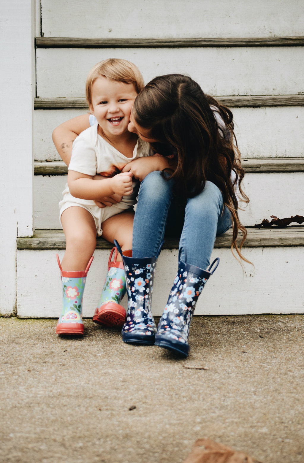 Blue floral rain boots worn by child, pull-on style with pink and orange flowers