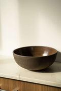 Stoneware fruit bowl, dark brown with speckled glaze, wide round shape.