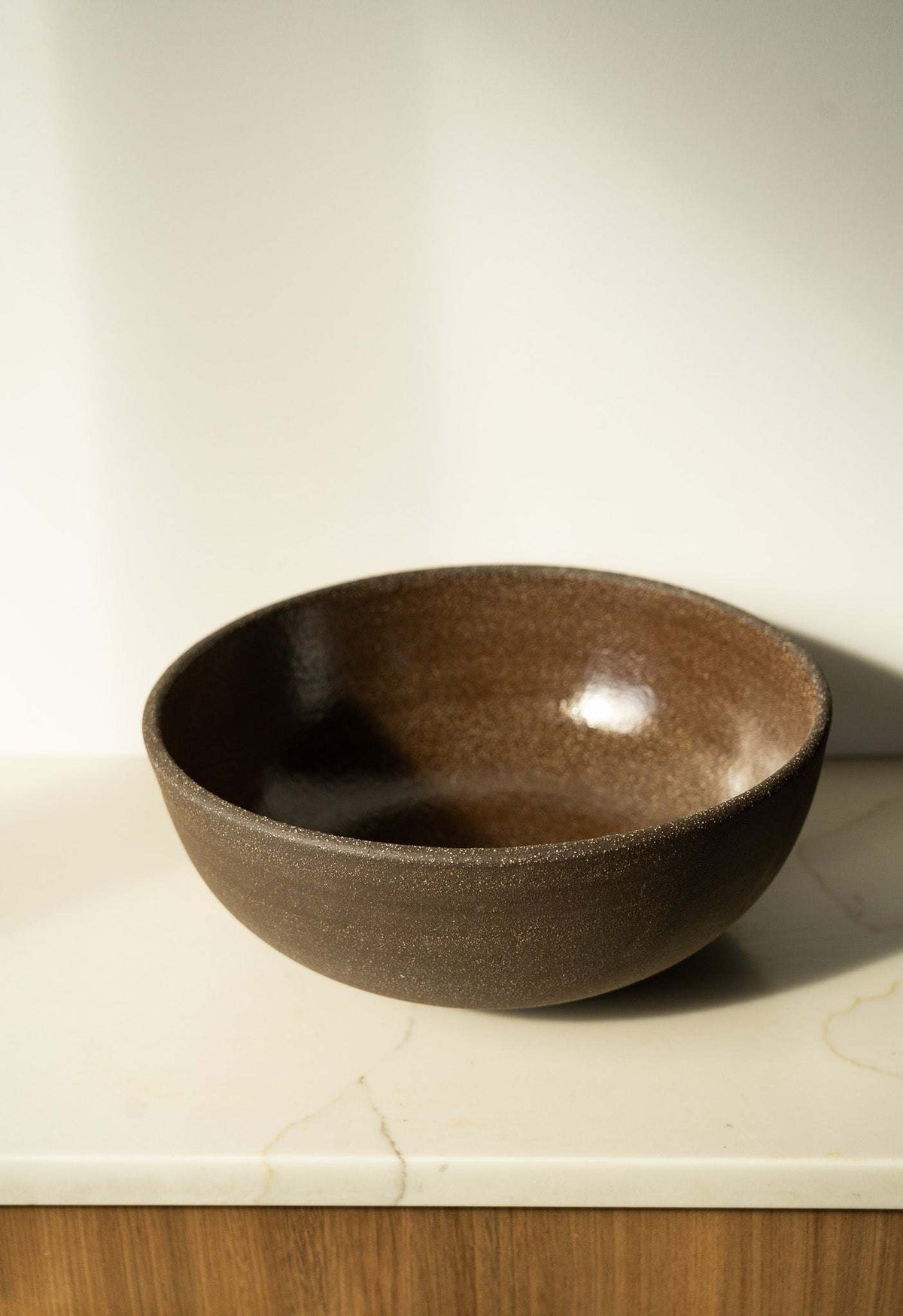 Stoneware fruit bowl, dark brown speckled glaze, shallow round interior.