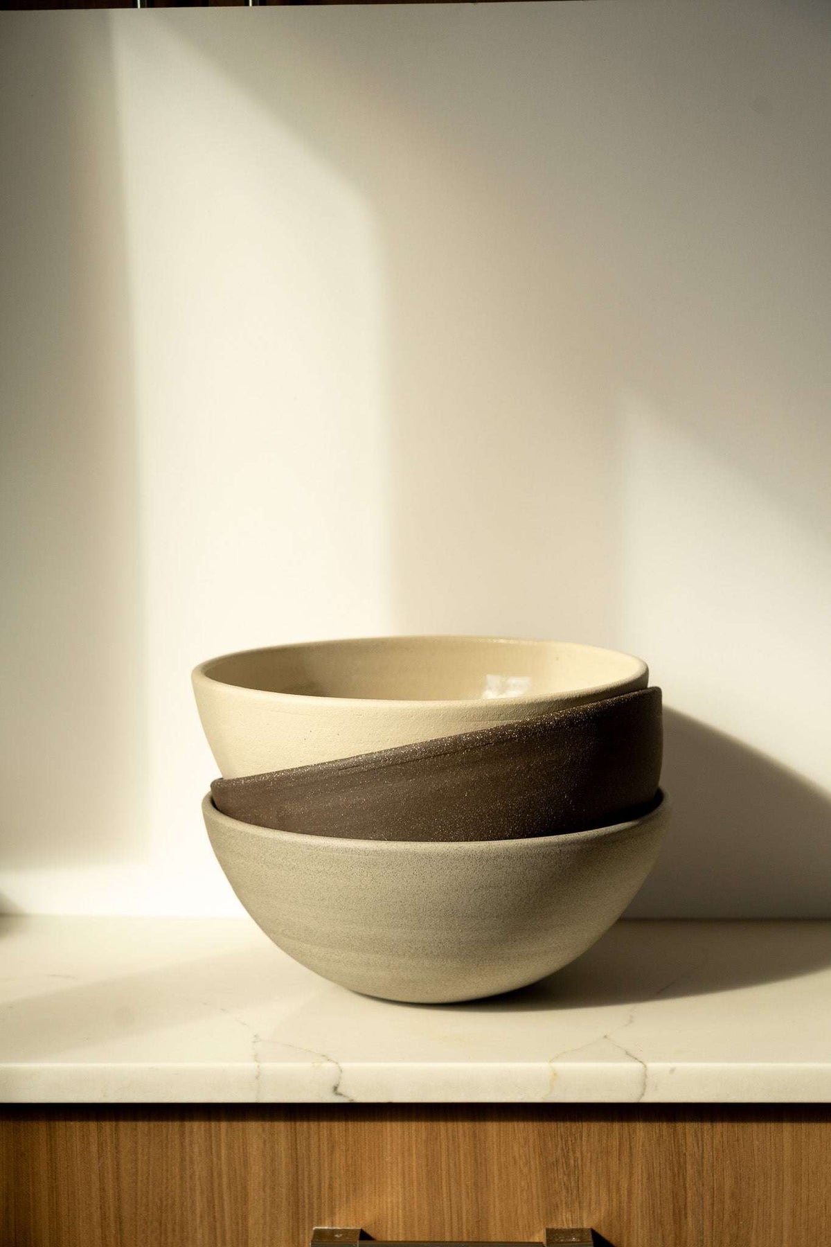 Stoneware fruit bowl display: light beige bowl with dark bowl nested inside.