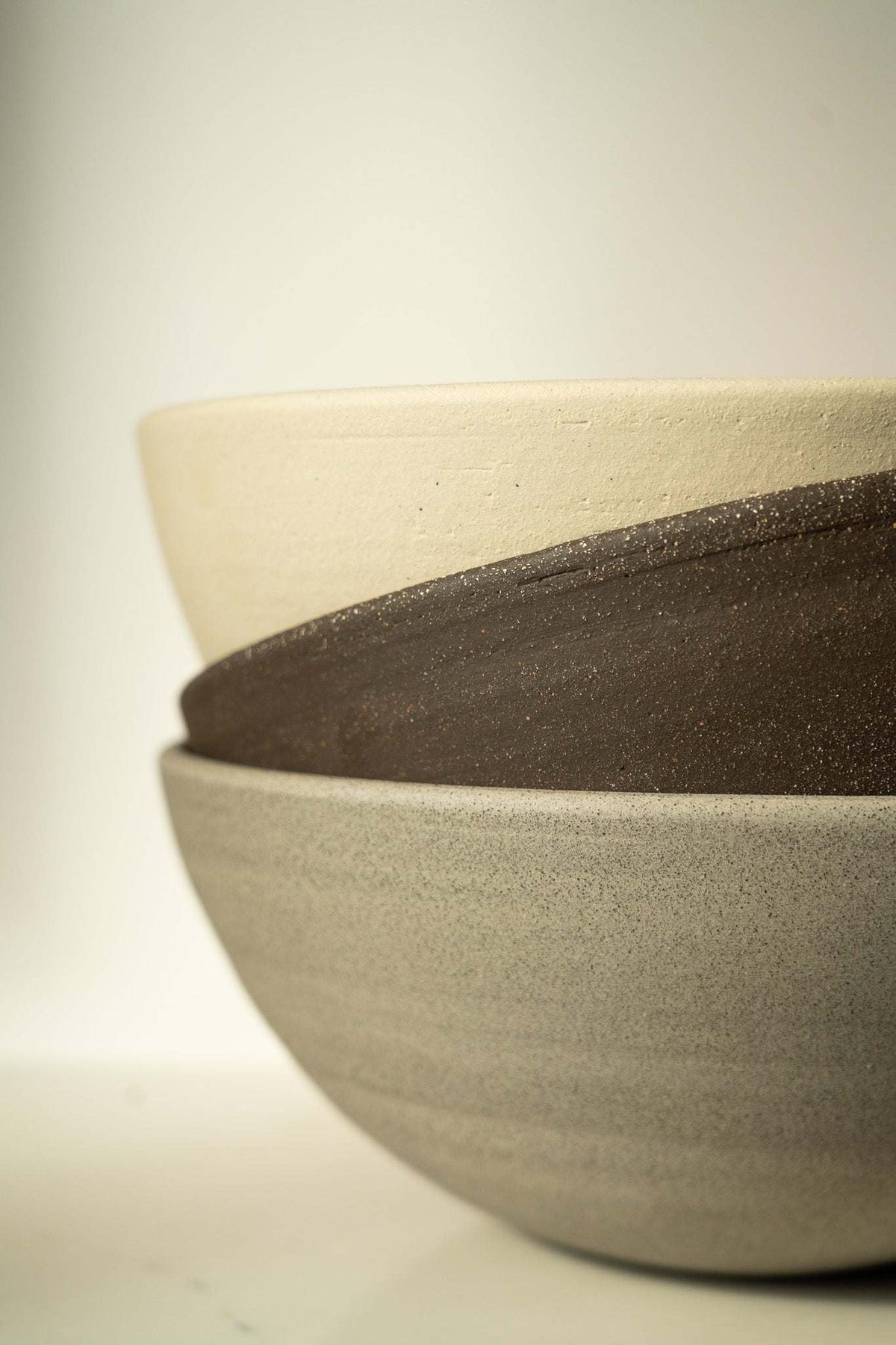 Stoneware fruit bowl rim detail, speckled dark edge with light beige bowl body.