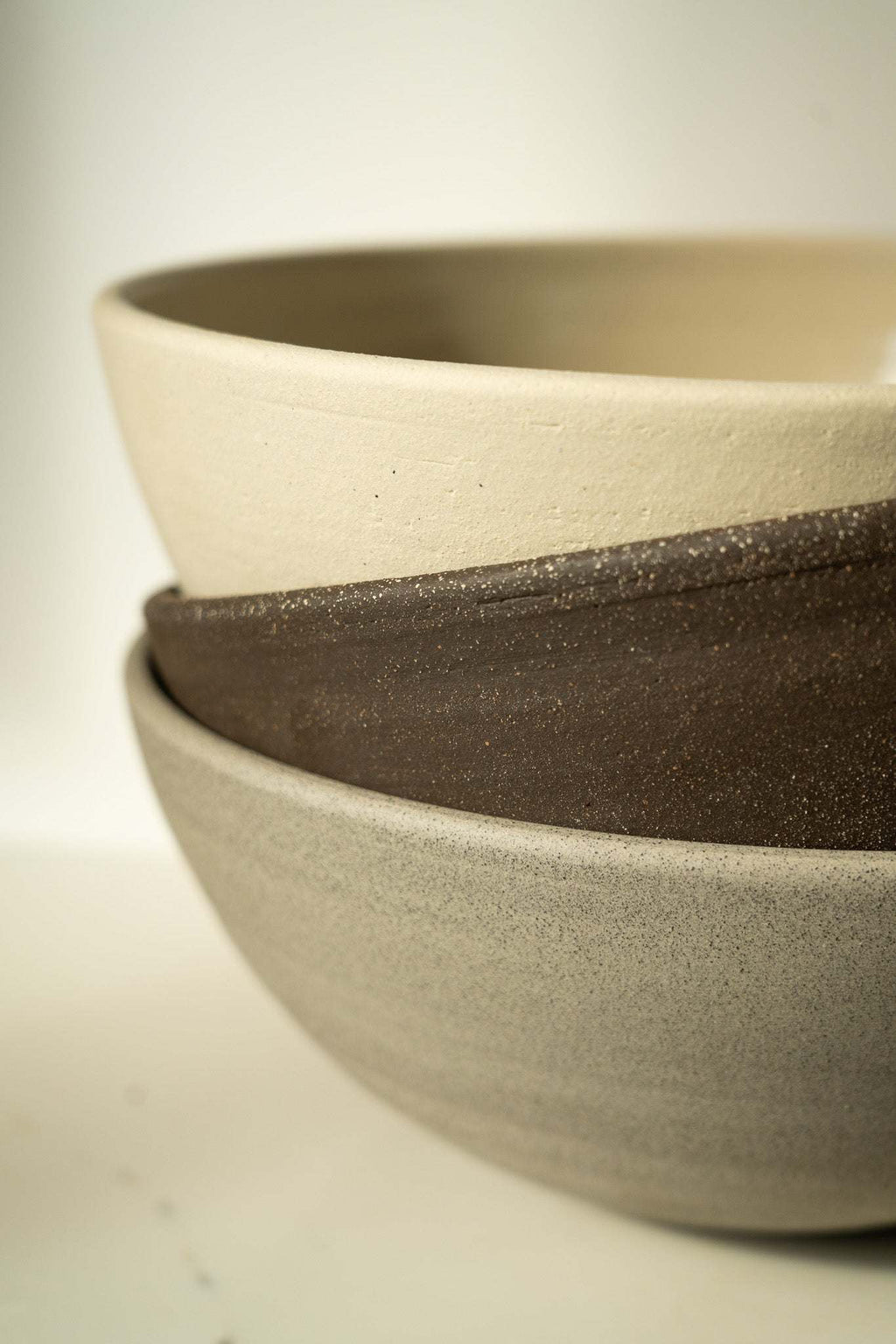 Stoneware fruit bowl rim detail, layered dark and light speckled stoneware.