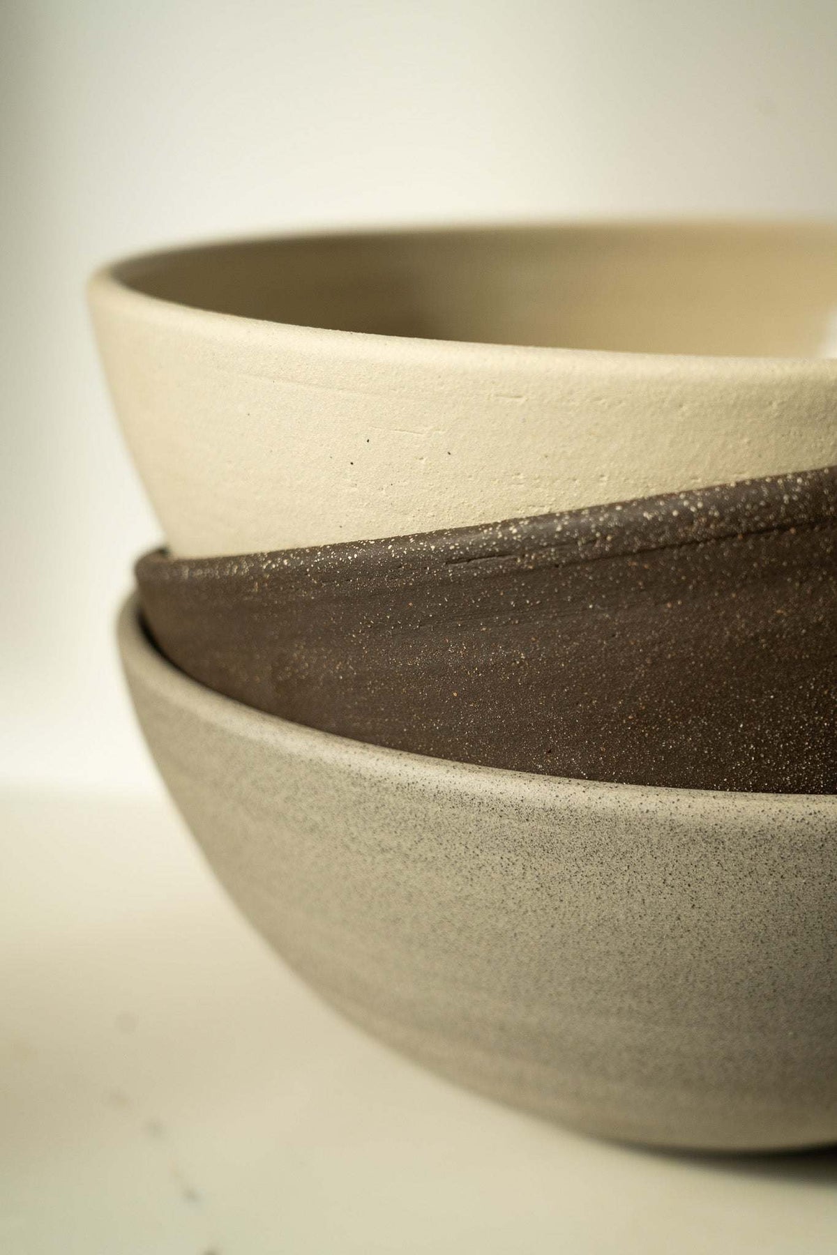 Stoneware fruit bowl rim detail, layered dark and light speckled stoneware.