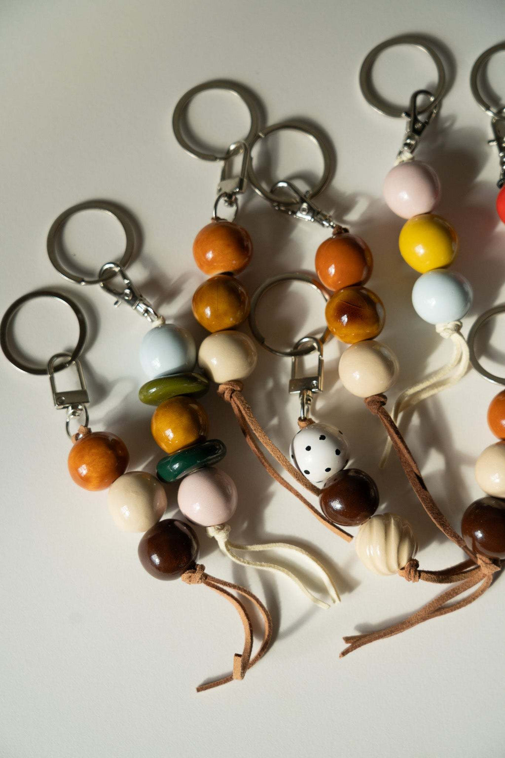 Multiple ceramic keychains with mixed beads, metal keyrings, and dangling tassels