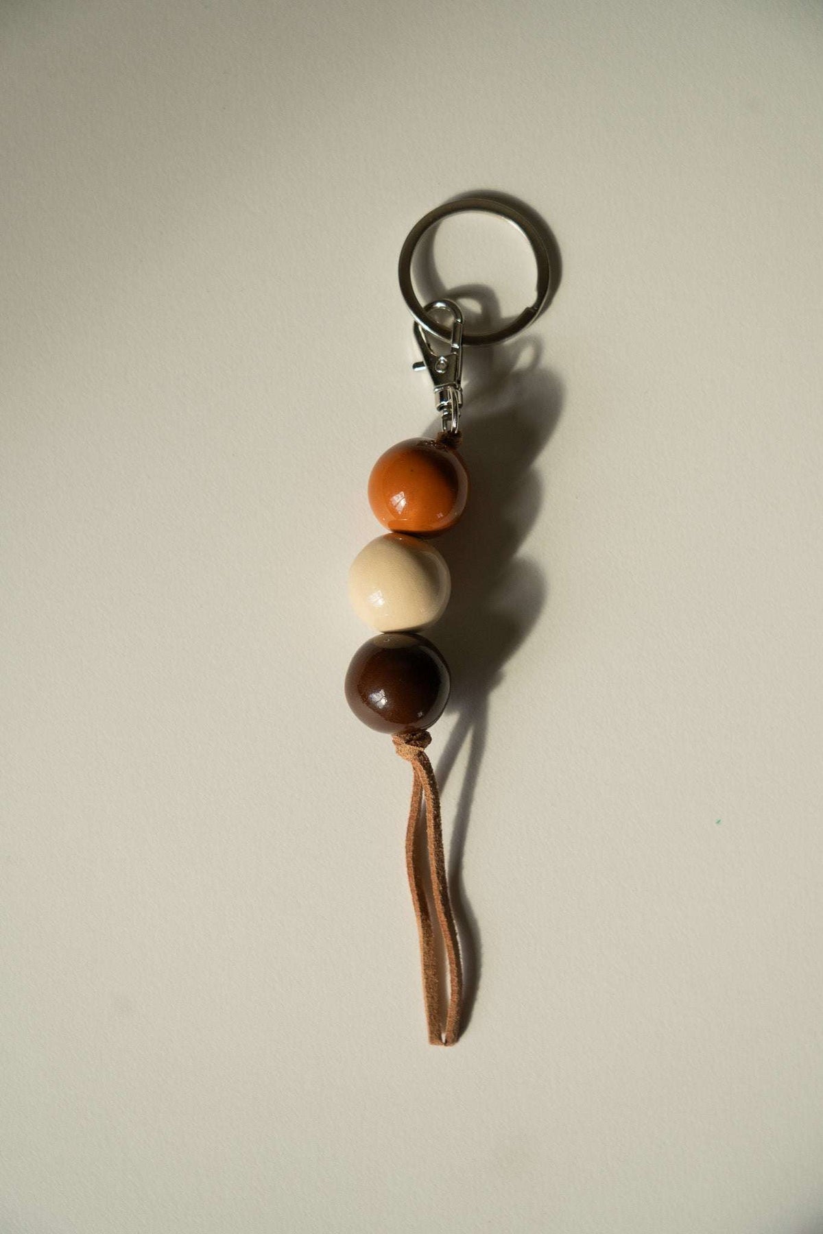 Handmade ceramic keychain with dark brown, cream, and orange beads and a tassel