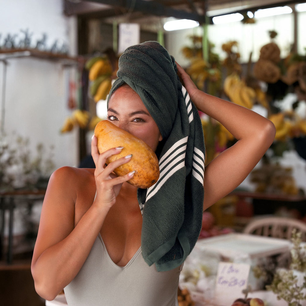 Cotton dark green towel with white stripes, wrapped on head and held
