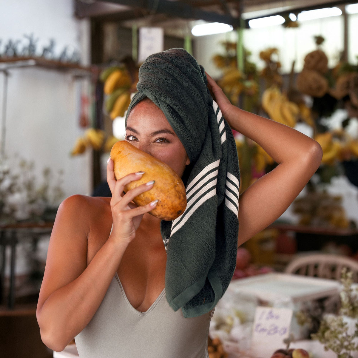 Cotton dark green towel with white stripes, wrapped on head and held