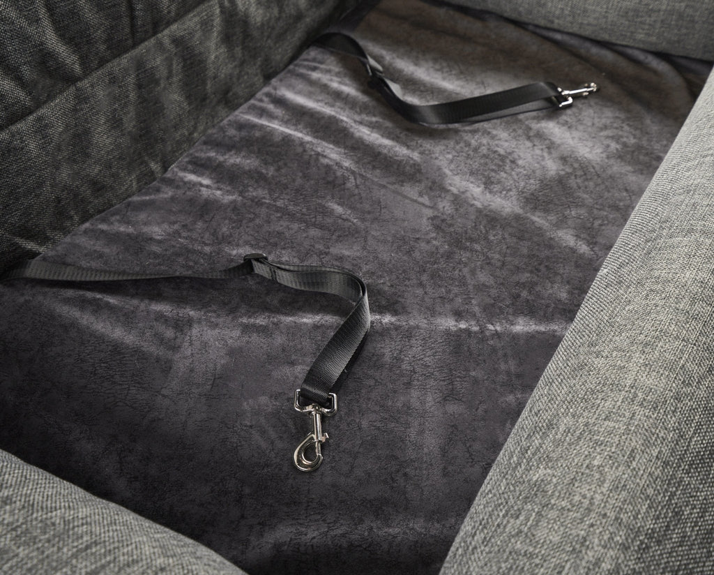 Gray dog car bed interior with security strap webbing and metal clips.