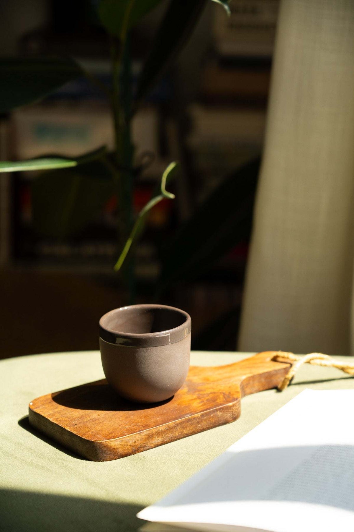 Handmade brown porcelain espresso cup on a wooden saucer tray