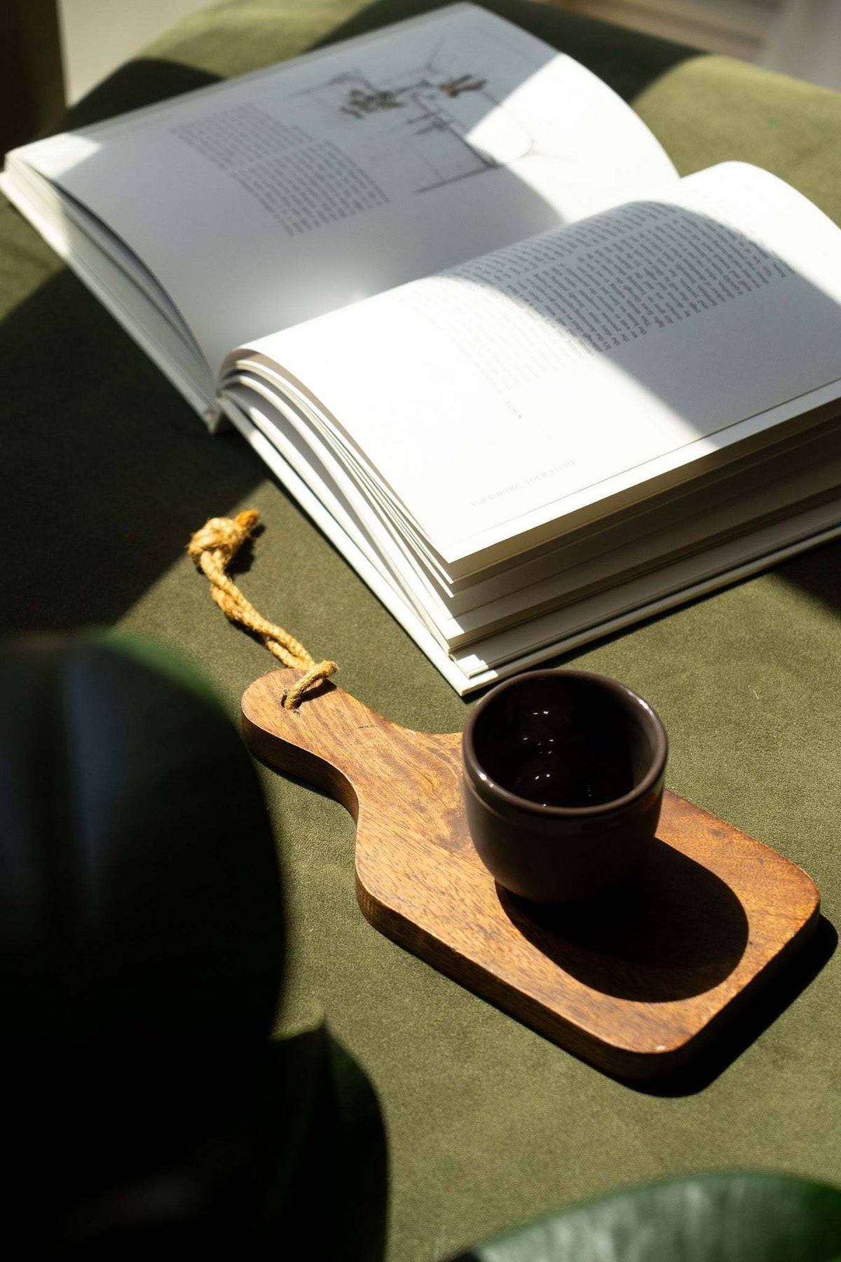 Handmade porcelain espresso cup with dark interior, on a wooden serving tray