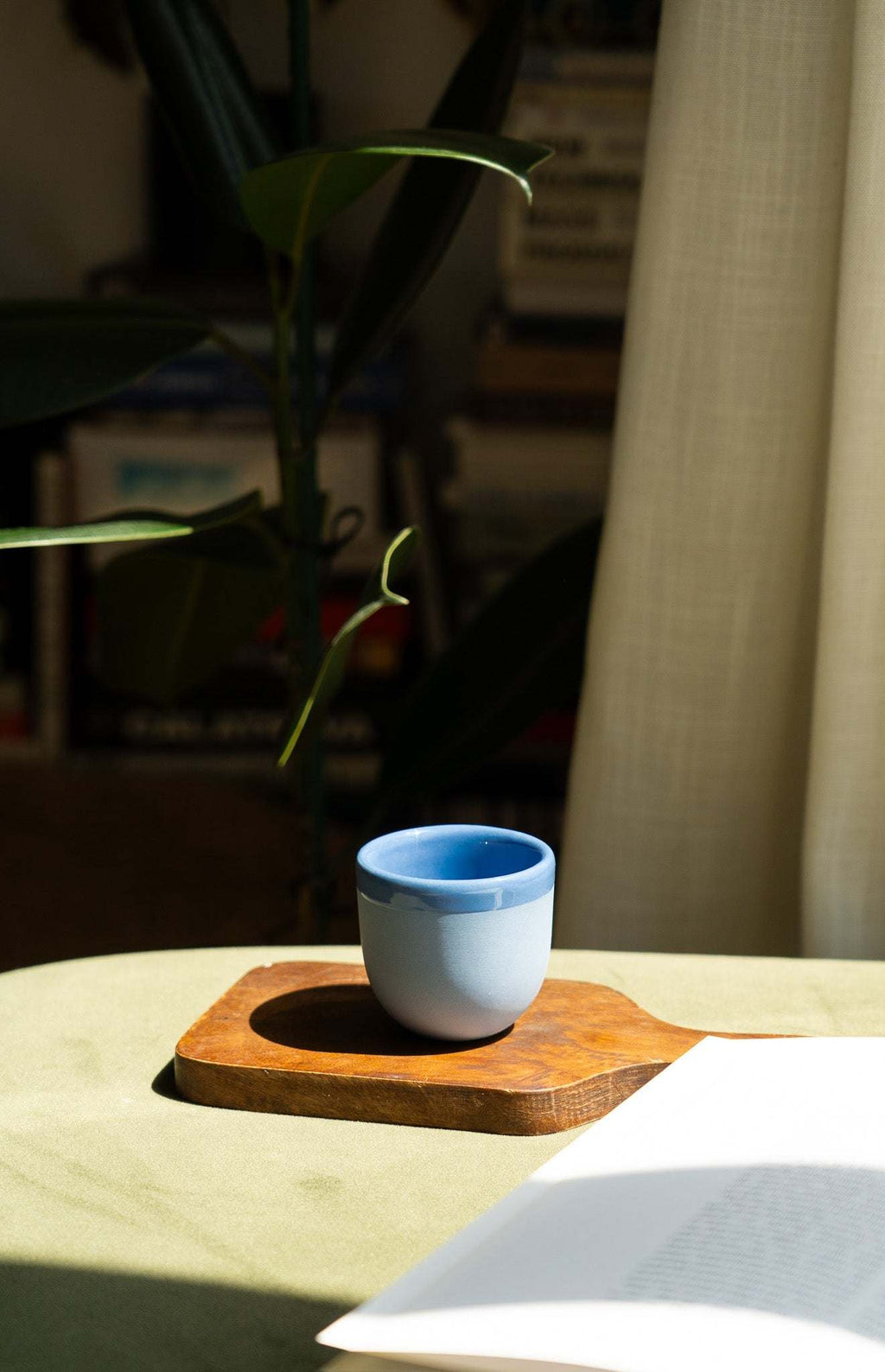 Handmade blue porcelain espresso cup with white exterior on a wooden tray