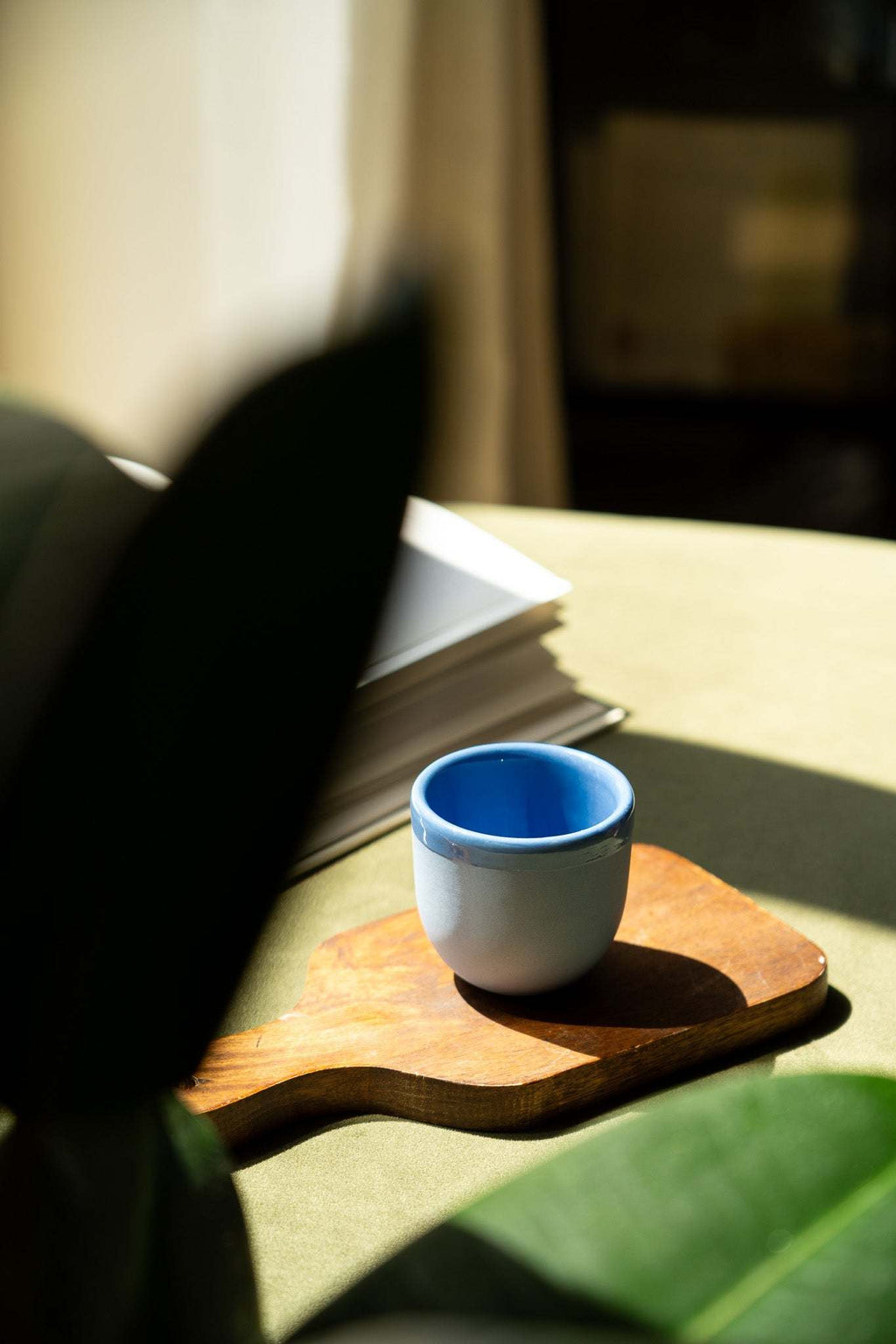 Handmade blue porcelain espresso cup on a wooden saucer tray