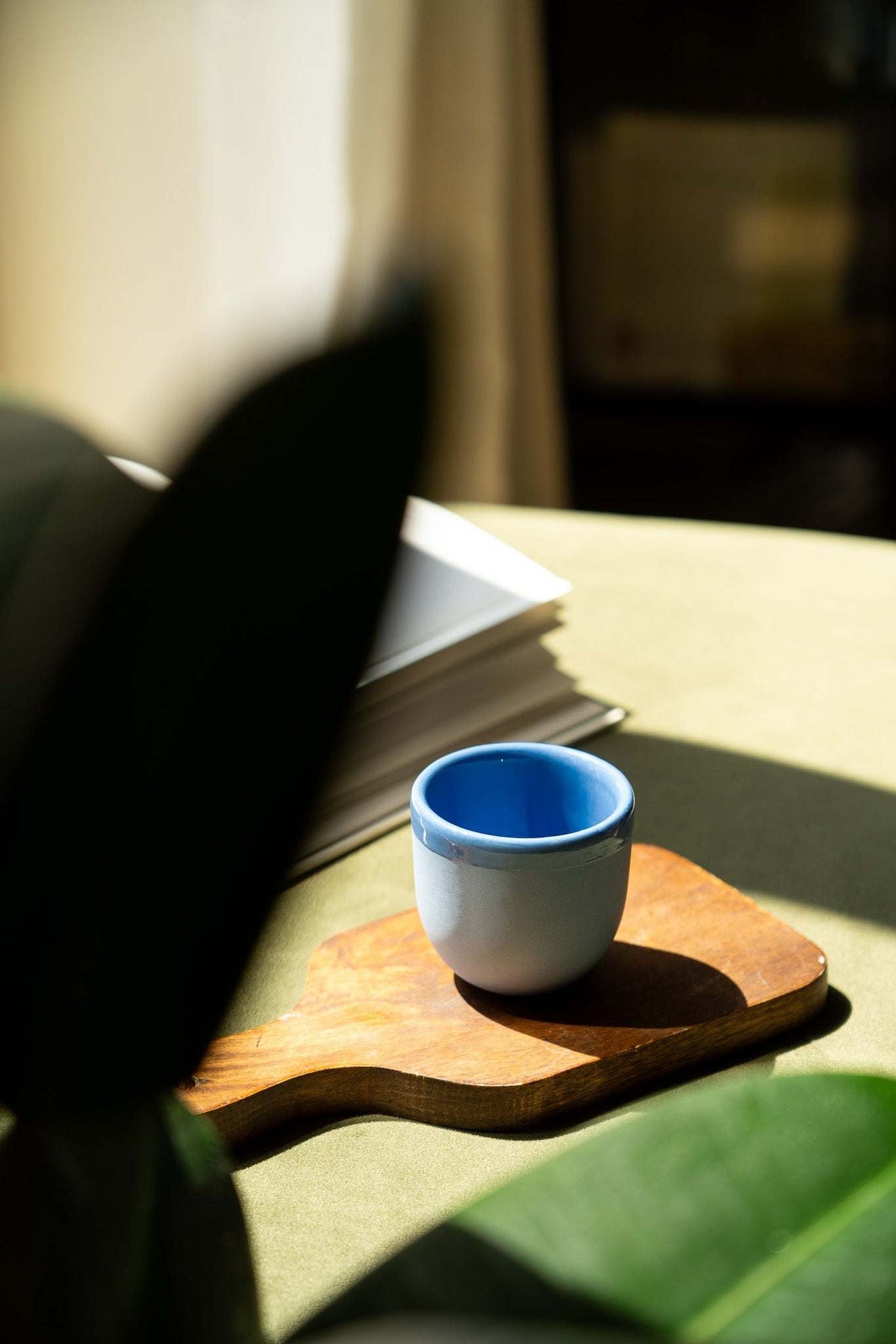 Handmade blue porcelain espresso cup on a wooden saucer tray