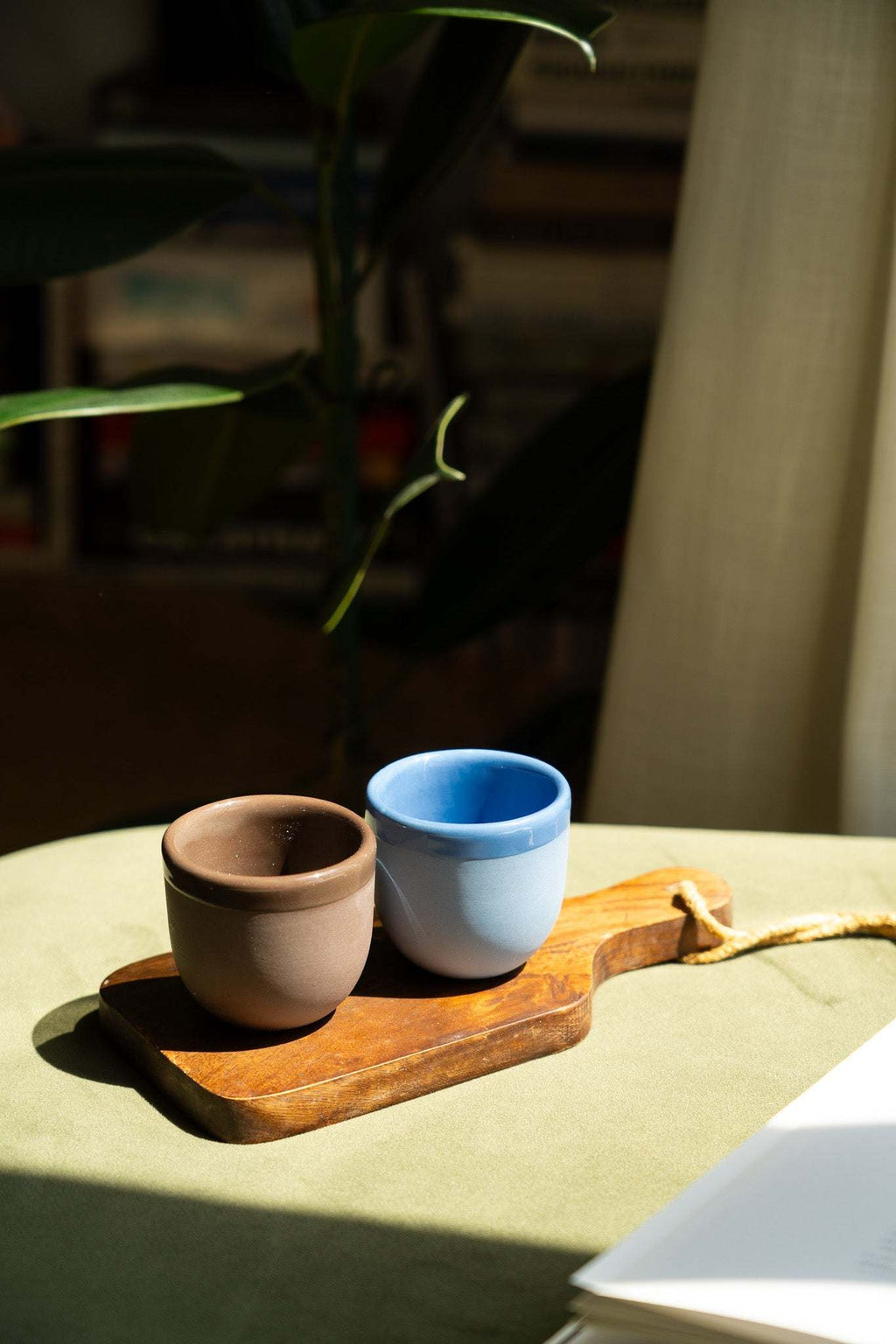 Pair of handmade porcelain espresso cups—blue and brown—on a wooden serving tray
