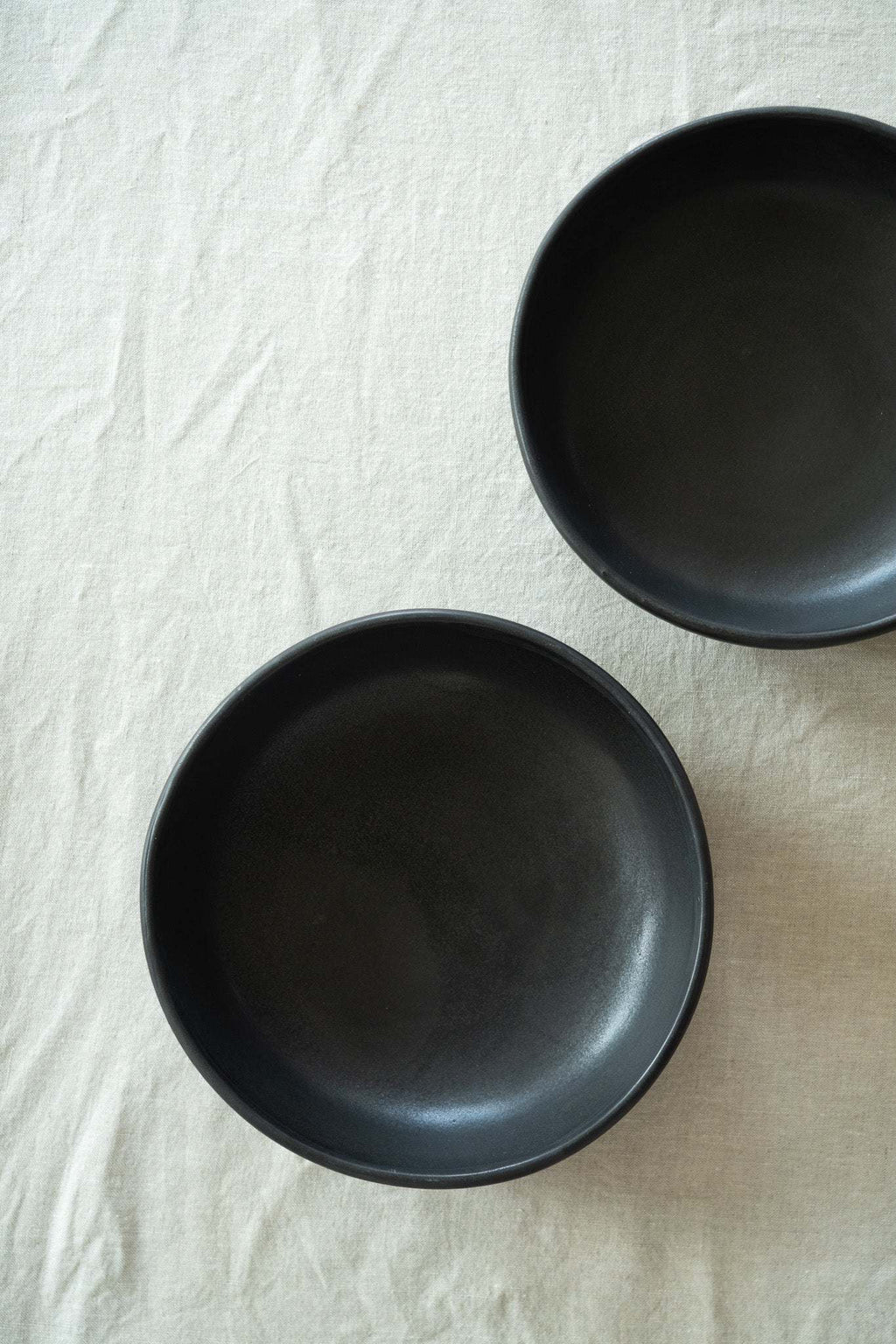 Pair of black matte stoneware pasta bowls, empty, side by side