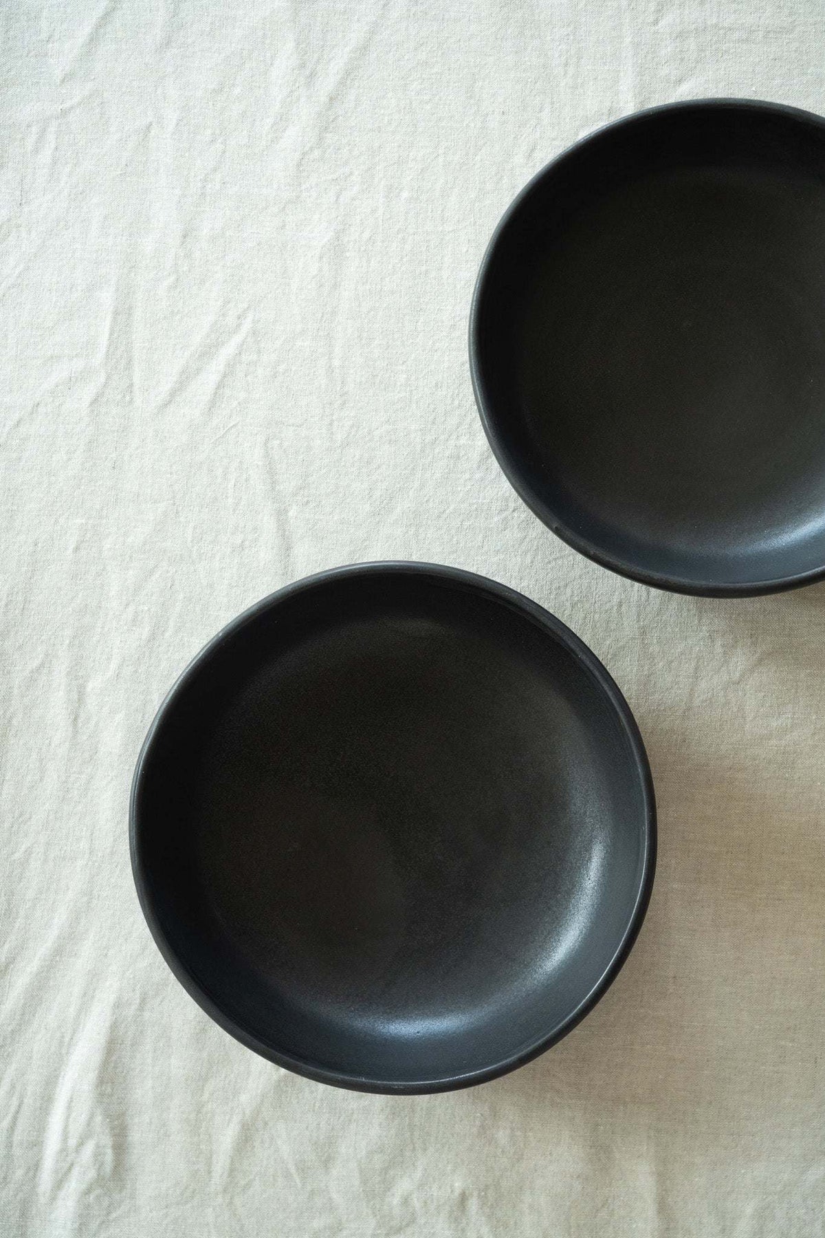 Pair of black matte stoneware pasta bowls, empty, side by side