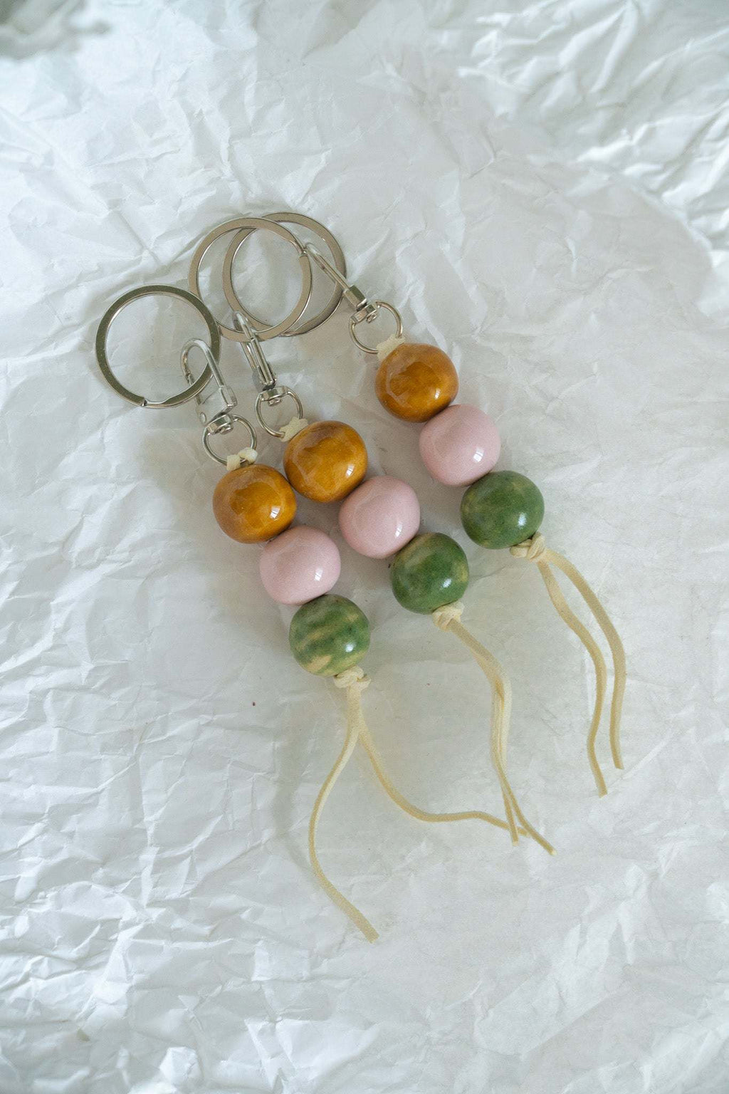 Ceramic bead keychains with metal rings, orange and pink beads, green beads, white tassel cords