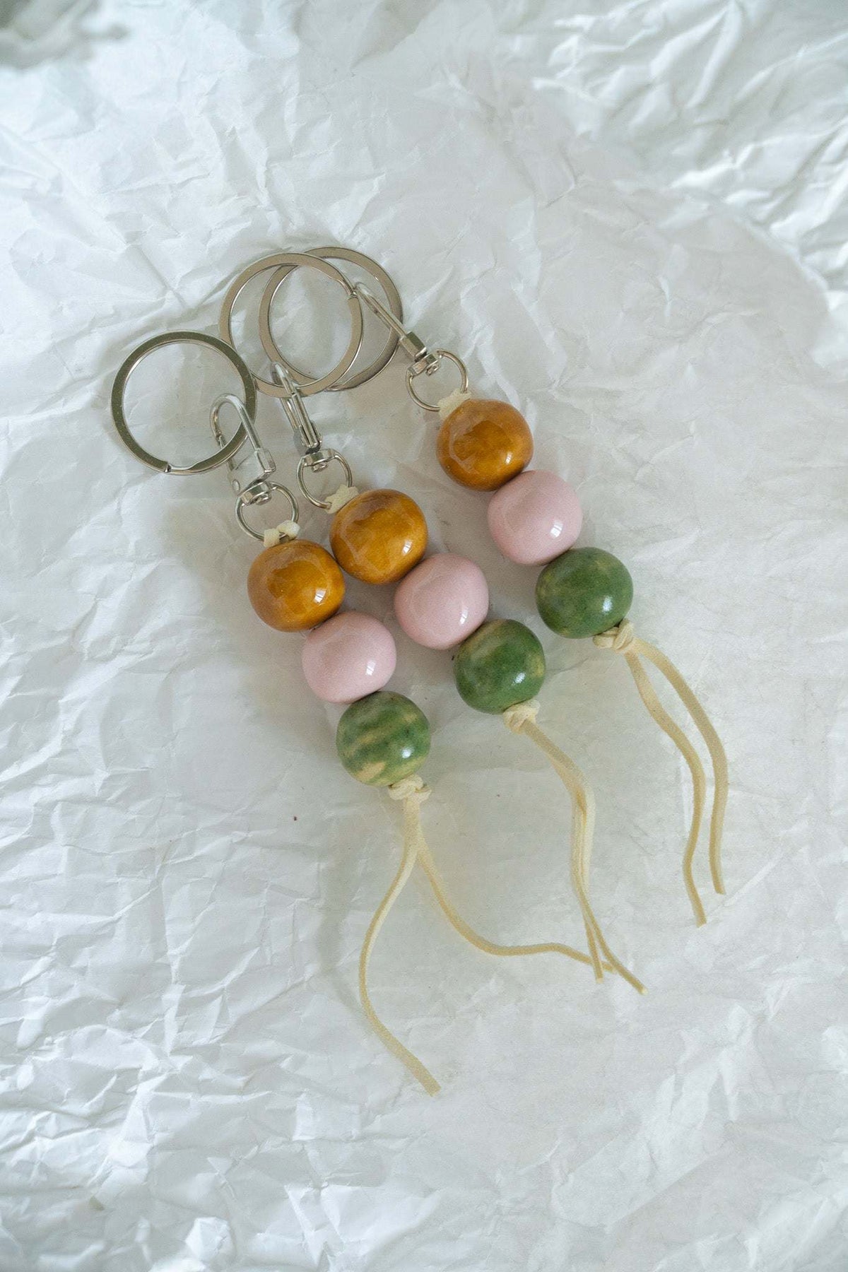 Ceramic bead keychains with metal rings, orange and pink beads, green beads, white tassel cords