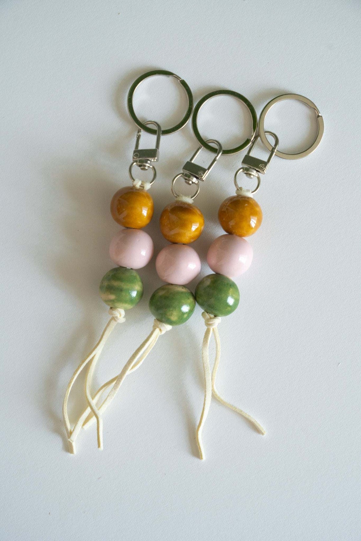 Ceramic bead keychains with multiple metal rings, orange, pink, and green beads, white cord tassels